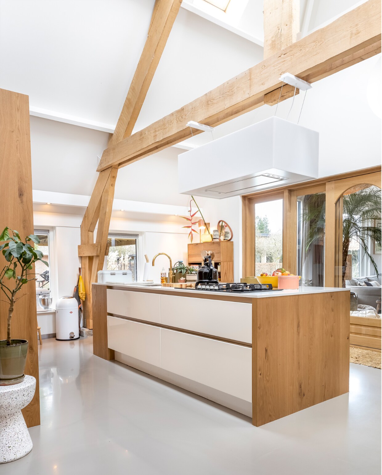 Muurverf en verf plafond Ral 9010, vloer gietvloer. Kruk links, kast en roze doosje HKliving. Keuken Smit Keukens. Pedaalemmer Wesco. Schort Witloft. Kraan Quooker. Fluitketel Le Creuset. Fruitschaal Des Pots. Afzuigkap Novy. Op de kast: lamp It’s About Romi, spiegel Zara Home, vaas MD Living, bloem Little Shop of Flowers. Overig onbekend. vtwonen 02-2023 | styling Karin van Schie | fotografie Henny van Belkom
