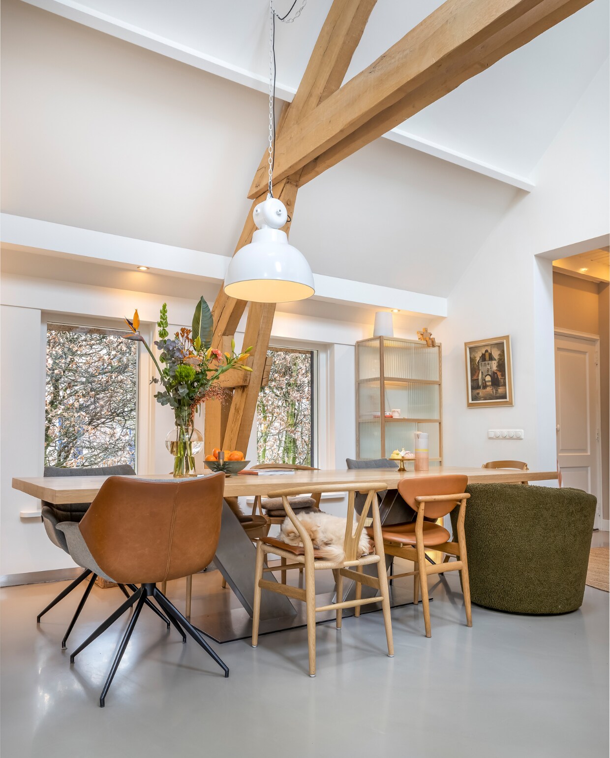 Muurverf en verf plafond Ral 9010, vloer gietvloer. Kuipstoelen Zuiver, overige stoelen MisterDesign. Kandelaar Sissy-Boy. Taartplateau H&amp;M. Kan, hanglamp en vitrinekast HKliving. Schilderij antiekmarkt. Overig onbekend. vtwonen 02-2023 | styling Karin van Schie | fotografie Henny van Belkom