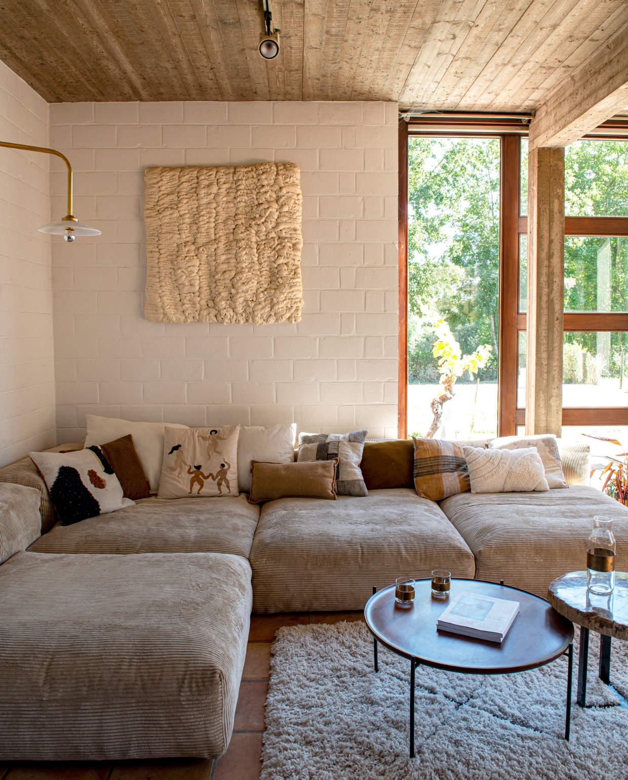 Lamp Muller Van Severen van Valerie Objects via La Fabrika. Bank Vetsak. Kunstwerk zelfgemaakt met isolatieschuim. Salontafels Swapp.Tapijt Ikea. Kussens Ferm Living en Zara Home. Lamp aan het plafond zat al in het huis. Glaswerk op tafel Serax. vtwonen 03-2023 | styling Jeske Weel | fotografie Caroline Coehorst