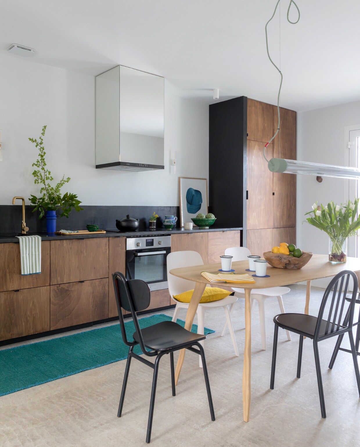 De keuken is zelf ontworpen en op maat gemaakt. Aanrechtblad en anhydriet gietvloer Mercadier. Afzuigkap Klarstein. Tafel Atelier Cédric Breisacher. Zwarte Mallet-Stevens-stoel rechts gevonden op straat, beige stoelen Odger Ikea. Led tl-lamp Tjoep Fatboy. Blauwe vaas en theedoek Conran Shop. Vloerkleed Atacama Élitis. Overig onbekend. vtwonen special binnenkijken 11-2022 | productie &amp; styling Marie Maud Levron | fotografie Cecile Perrinet-Lhermitte