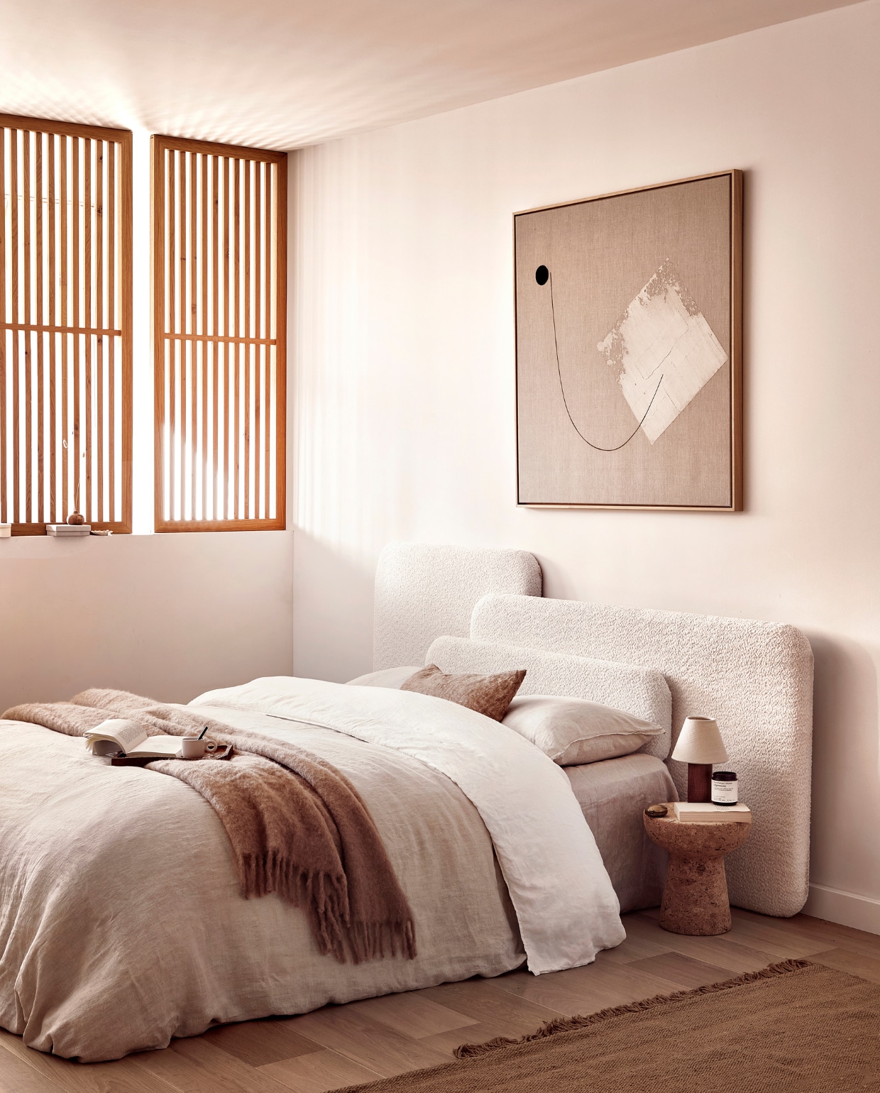 Wit linnen dekbedovertrek € 119,-, beige linnen dekbedovertrek € 119,-, wollen plaid € 89,-, tafellamp € 59,99 (zarahome.com). Kurken bijzettafel, 31x33cm (Øxh) € 429,- (homestede). Vloerkleed van Ferm Living, 300x200 cm € 595,- (vtwonen.be). Schilderij prijs op aanvraag (tessaderijk.com). Houten dienblad € 24,99, grijze mok € 4,99 (hm.com). Overig privébezit. vtwonen 03-2023 DIY large | styling Sanne Ketelaar | fotografie Peggy Janssen | assistentie Evans van der Sluis, Paul Blom