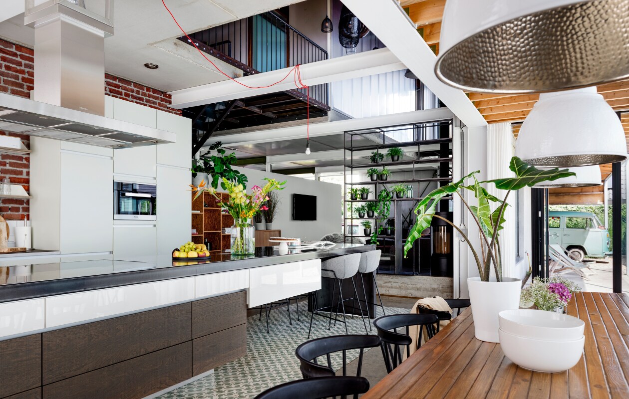 Keukenkasten ontwerper Studio Boomm, maker Romein Maatinterieurs. Keukeneiland rvs en blauwstaal ontwerp en uitvoering Studio Boomm. Houten kast gemaakt door Romein Maatinterieurs. Barkrukken Feston van Zuiver, Portugese vloertegels Azule VN Chateau 10 Olive Designtegels, keukenmachine Kitchen Aid, vaas Sissy Boy, Lamp onbekend. vtwonen 07-2020 | styling Moniek Visser | fotografie Stan Koolen