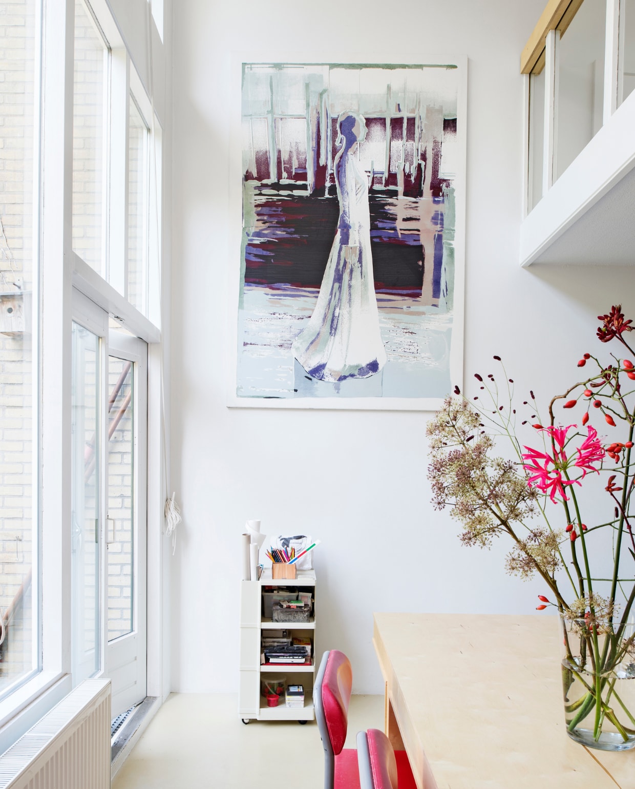 Verfkleur gietvloer Ral 9002, muurkleur signaalwit Ral 9003. Het schilderij kregen ze cadeau van kunstenaar en vriendin Saskia Gottenbos. De trolley is een designklassieker van Joe Colombo. De Ettore Sottsass-stoelen komen uit het ouderlijk huis van Godert. vtwonen mei 2015 | Fotografie Louis Lemaire | Styling Susanne Kennedy |