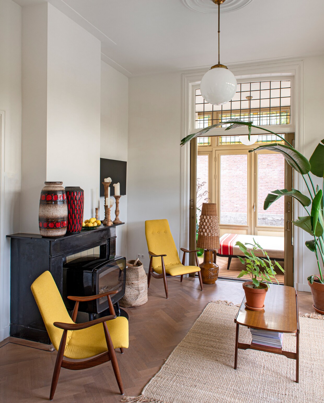 De haard en schouw zaten al in het huis. Ook de serredeuren zijn nog origineel. Vazen uit Berlijn. Kandelaars Zutphense Hand. Louis van Teeffelen-fauteuils en vloerlamp Vanouds Schalkhaar. Mand Sissy-Boy. Hanglamp Marktplaats. Vloerkleed Stilleven. Bed in serre Cleopatra van Auping. Deken Marktplaats. Overig onbekend. vtwonen 03-2023 | Styling en fotografie Caroline Coehorst i.s.m. Studio Daan Hietbrink