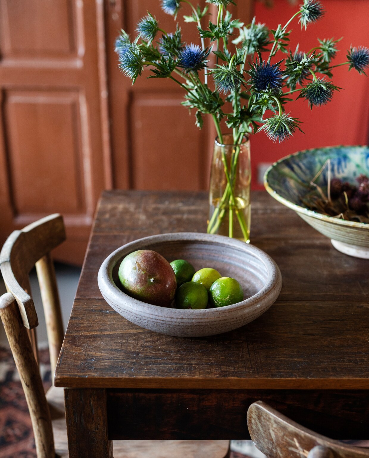 Tafel op maat gemaakt van gerecyclede teak vloerdelen door Jan van IJken. Schaal links vintage, rechts Pols Potten, vaas Loods 5, stoelen Burbri, kast vintagemarkt. vtwonen 03-2023 | Styling Ilona Jongepier | Fotografie Dana van Leeuwen