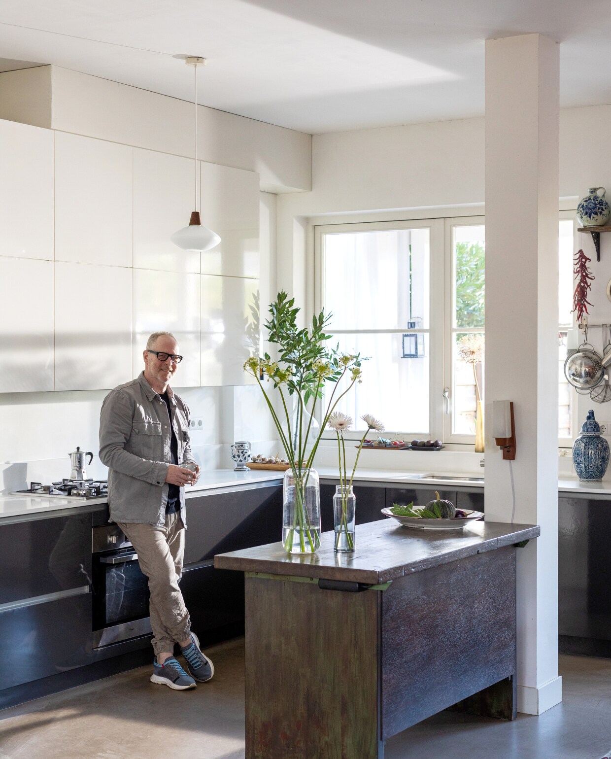 Keuken Kvik met composiet werkblad, kookplaat, fornuis Siemens, vintage werkbank Werkplaats 35, hanglamp, wandlamp, Delftsblauwe vaas en houten schaal kringloop, koffiekan Bialetti, vazen Fést Amsterdam en kringloop, schaal vensterbank Vintage Asylum, schaal op werkbank The Fine Store. Muur- en houtverf in Quiet Blush van Lab Paint van Vestingh. vtwonen 03-2023 | Styling Ilona Jongepier | Fotografie Dana van Leeuwen