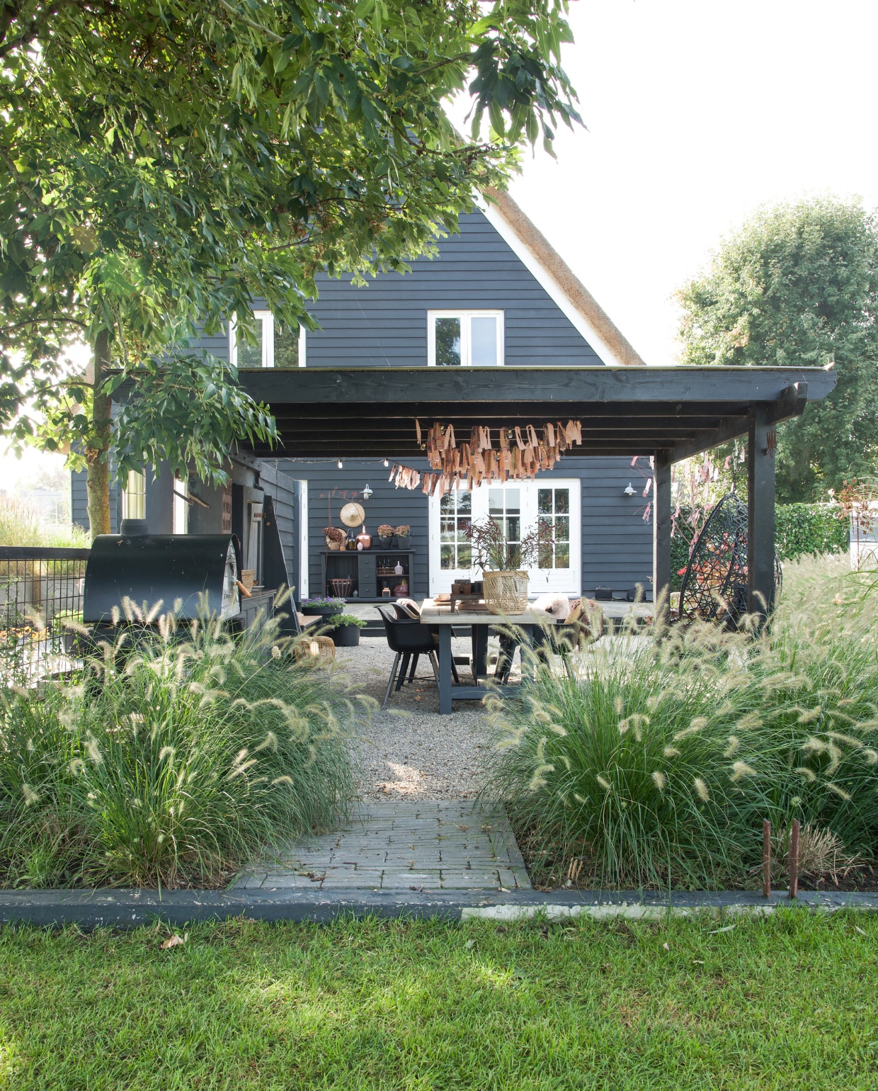 Eettafel Tuinmeubelshop Gouda, stoelen Kwantum. Servies Hema, glazen en bestek H&amp;M Home, placemats bol.com, vacht Ikea, kleed Kwantum, discobol kringloop, mand Kwantum, kaarsenstandaard en verroest tafeltje met waxinelichtjes Loods 5. Rechts een oude duiventil, gekregen van een buurman. Slingers boven tafel zelfgemaakt van stoffen van de kringloop. vtwonen special tuin 07 | styling Marieke de Geus | fotografie Barbara Groen