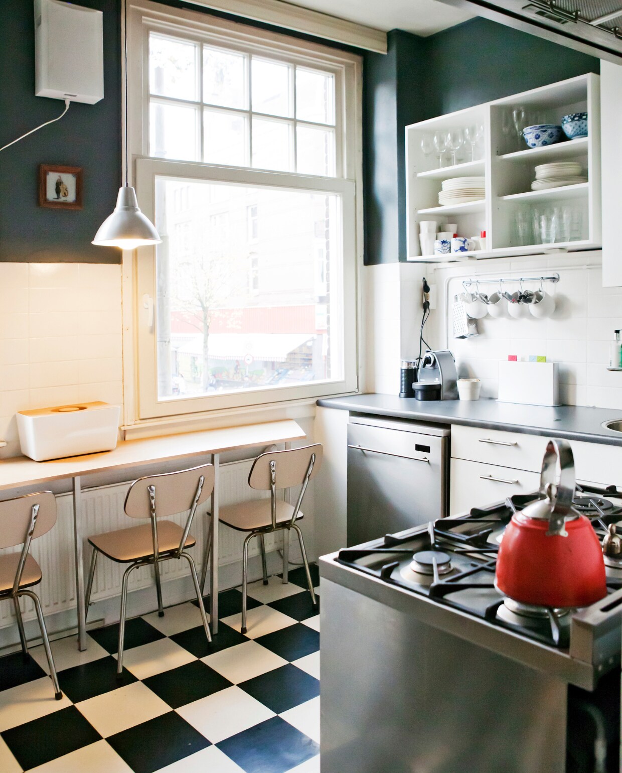 De muurkleur in de keuken is Down Pipe van Farrow &amp; Ball. De kleur verandert met het licht en is dus steeds een beetje anders. De stationsklok was een cadeau. In de keuken ligt zwart-wit geblokt zeil. Het zespits fornuis is van Smeg. vtwonen 12-2013 | fotografie Barbara de Hosson