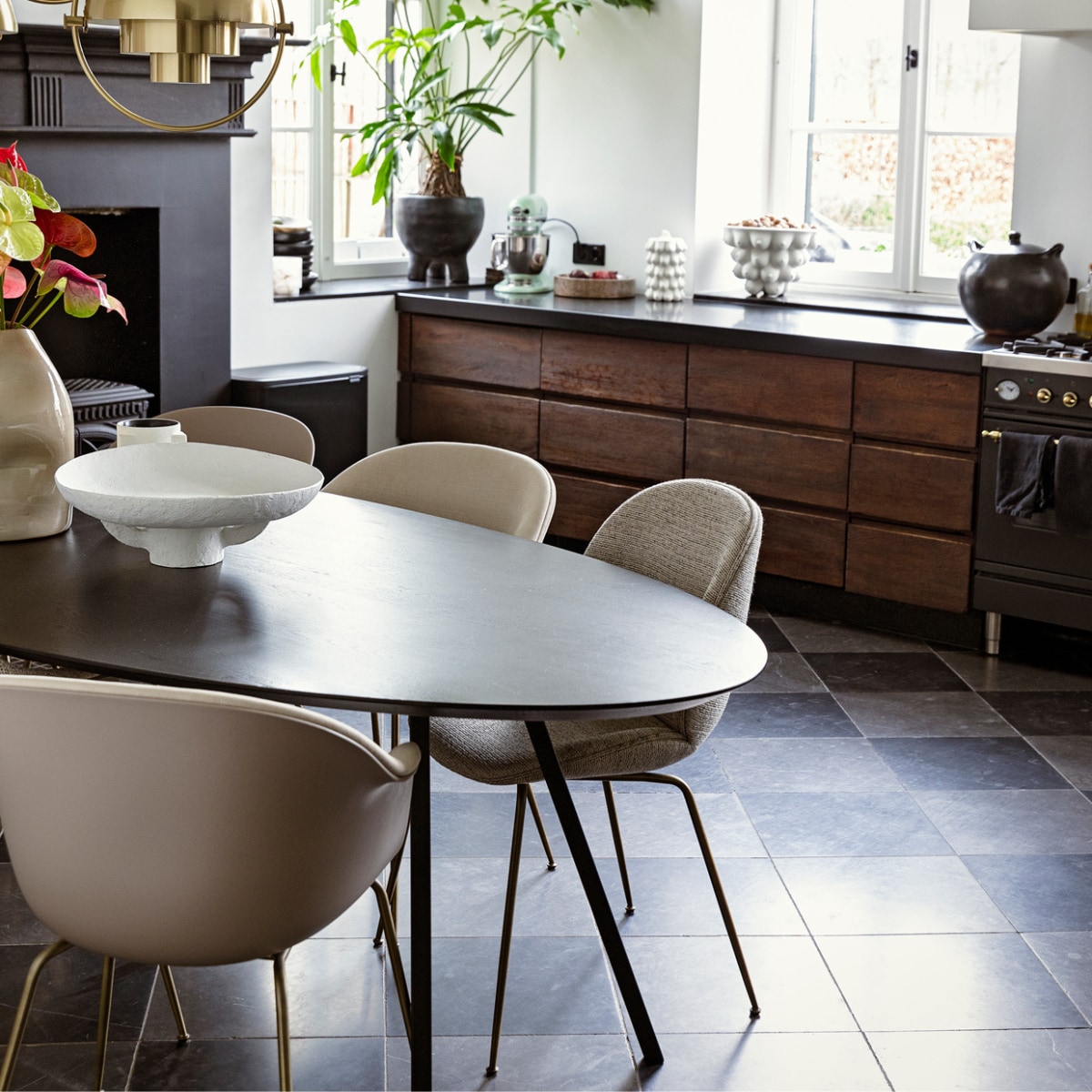 Tafel Studio Henk. Plafondlampen en stoelen Bat en Beetle van Gubi via Interior Playground. Schaal Serax. Kaars l’Objet. Vaas Casa Gitane. Schilderij Art in Return. Plantenpot Ames Design. Op het aanrecht: schaal Ferm Living. Koekjespot en schaal Jonathan Adler. Pan Indigena Fine Folk Art. vtwonen 11-2021 | Styling ilona jongepier | Fotografie dana van leeuwen