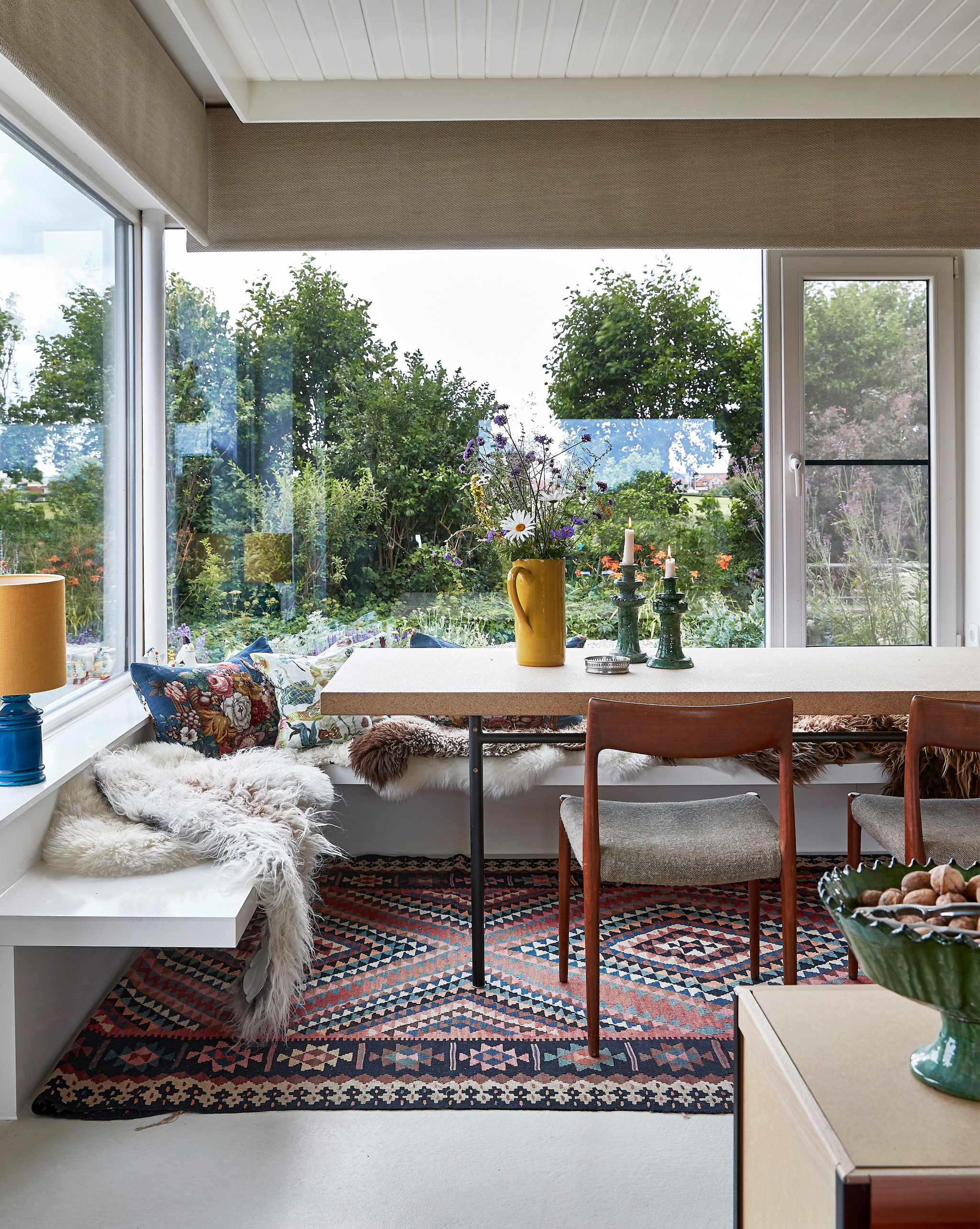 Bank en kussens zelfgemaakt. Schapenvachten her en der gekocht. Tafel Sinnerlig Ikea. Stoelen familiestukken. Schenkkan Villa Augustus. Kandelaars en groene schaal uit Marokko. Vloerkleed uit Istanboel. Tafellamp tweedehands. vtwonen special binnenkijken 2022 | productie Living Inside | fotografie Jan Verlinde