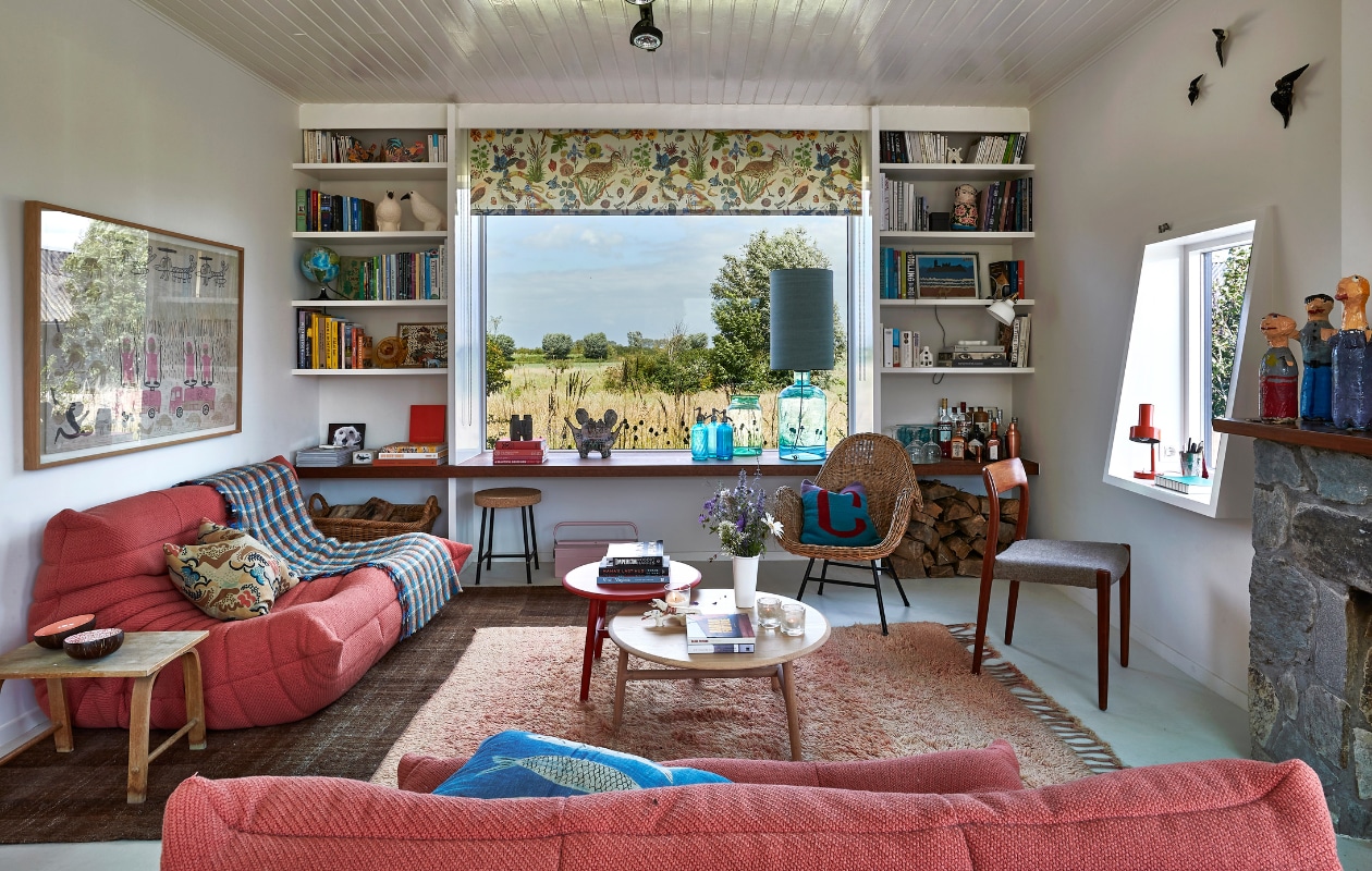 Banken Togo Ligne Roset. Vloerkleden en schilderij uit Marokko. Salontafels Sancal. Stoelen familiestukken. Blauw-rood kussen uit Georgië. Rolgordijn gemaakt van stof van Nathalie Lété. Blauwe lamp, flessen, vaas, kruk en wit lampje Ikea. Rode lamp rommelmarkt. Houten bijzettafel gevonden in de schuur. Vogels in boekenkast Villa Augustus. Overig onbekend. vtwonen special binnenkijken 12-2022 | productie Living Inside | fotografie Jan Verlinde