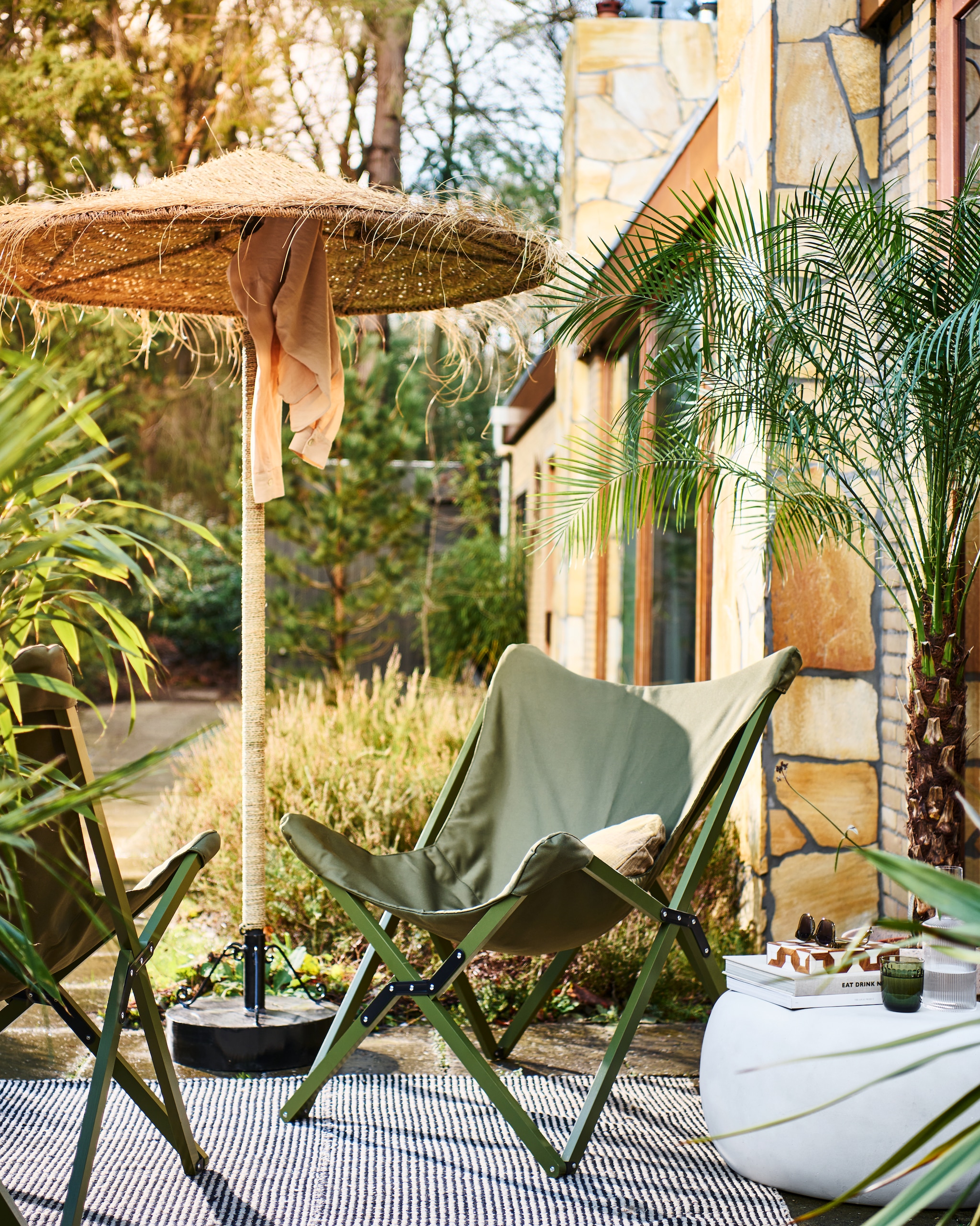 Opvouwbare buitenstoelen Lazy Afternoon in camouflage groen, 85x77x92 cm (bxdxh) € 169,-. Bijzettafel Pebble in betonlook wit, 65x49x31 cm (bxdxh) € 199,-. Ook verkrijgbaar in 50x35 cm (Øxh) € 179,- en in antraciet. M.m.v. householdhardware.nl (parasol, parasolvoet), vtwonen.nl (kussen, waterglas). Overig privébezit. vtwonen 04-2023 | productie Tanja Saarberg | styling Marlies Does | fotografie Sjoerd Eickmans
