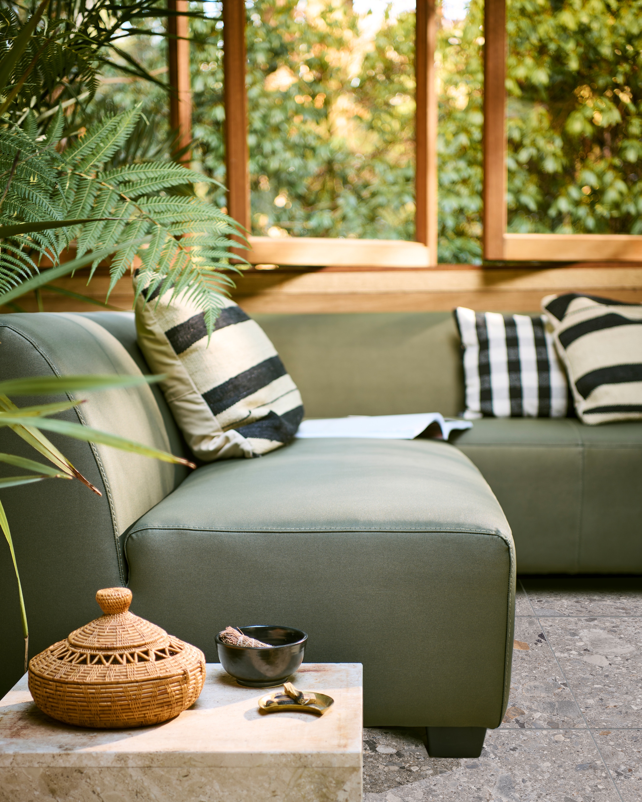Hoekbank Hollandia rechts in camouflage groen, 230x214x70 cm (bxdxh) € 1949,-. Ook verkrijgbaar in carbon grijs, als 3-zitter en als 2-zitter. Tuintegel Solostone Composite mix, 70x70 cm per m2 € 79,-. M.m.v: vtwonen.nl (groen velvet kussen van Hay, ecru kussen met groen/gele strepen, waterglas) aimelie.nl (geruite kussens), householdhardware.nl (grote okergele Tamegroute schaal). Overig privébezit. vtwonen 04-2023 | productie Tanja Saarberg | styling Marlies Does | fotografie Sjoerd Eickmans