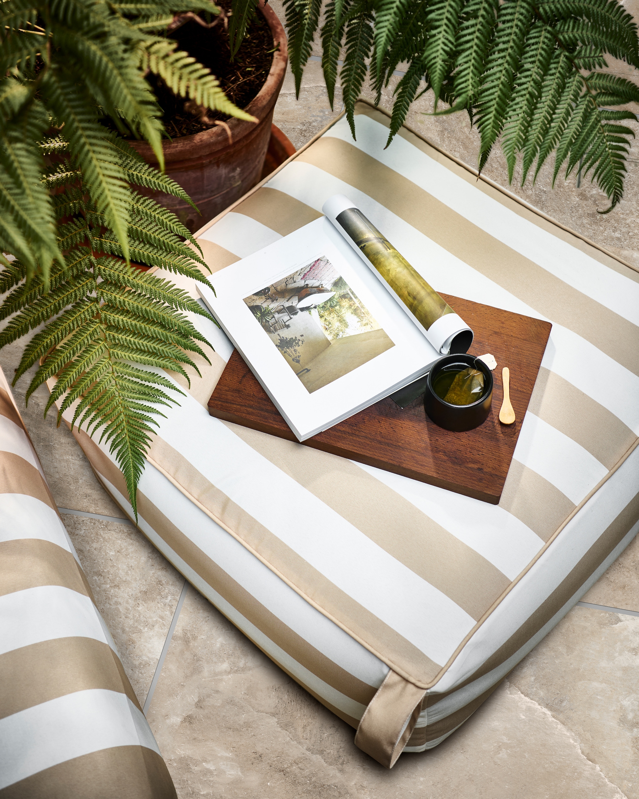 Opblaasbare poef Sit on Air in zand/wit, 72x72x35 cm (lxbxh) € 69,95. Ook verkrijgbaar in zwart/wit. Tuintegel Solostone Clouds, 70x70 cm per m² € 79,-. M.m.v. householdhardware.nl (zwarte mok). Overig privébezit. vtwonen 04-2023 | productie Tanja Saarberg | styling Marlies Does | fotografie Sjoerd Eickmans