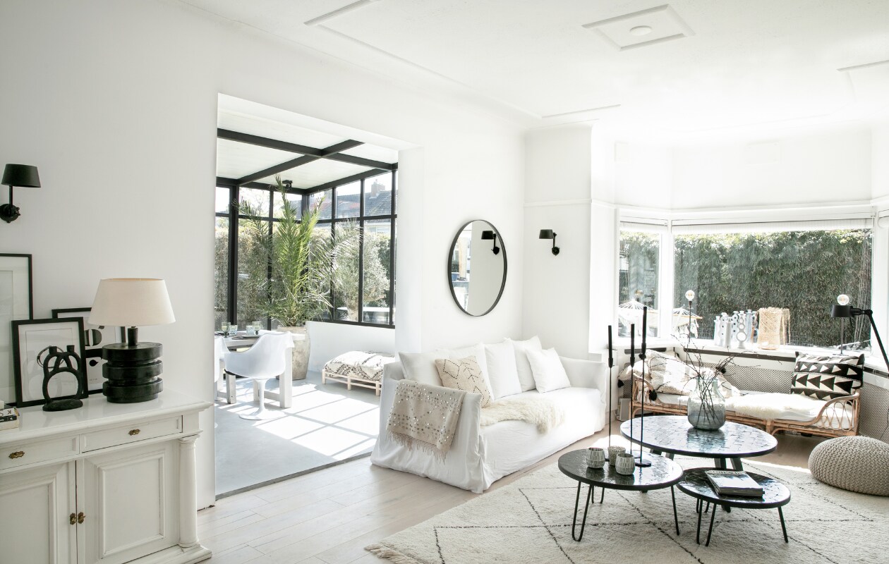 Bank Gervasoni, kaarsenstandaards Loft, plaid uit Marrakech, wandlampen Bolt van Tonone, spiegel Sissy-Boy, salontafels Zenza Home, lamp op buffetkast Casa Gitane, eetkamerstoelen Tulip van Eero Saarinen, eettafel eigen ontwerp, kruikplant Cooperz Wonen, XL poefbank Studio Pure, wandkleur Ral 9010, wit gelakte eikenhouten vloer. Overig onbekend. vtwonen 04-2023 | fotografie Monique Koelman