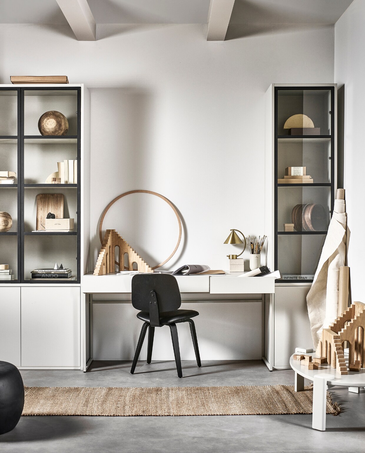 Grenenhouten bureau Basic in Mist, 150x50x76 cm (bxdxh) € 399,-. Stoel Classic in zwart, houten frame en leren zitting, 50x48x81 cm (bxdxh) € 149,-, ook met walnoothoutfineer frame. Rechts: grenenhouten vitrinekast Basic 2-deurs in Mist, 53x40x230 cm (bxdxh) € 749,-. Links: grenenhouten vitrinekast Basic 4-deurs in Mist, 101x40x230 cm (bxdxh) € 999,-. Mangohouten salontafel Turtle in Mist, 100x60x28 cm (lxbxh) € 399,-. Betonlook bijzettafel Pebble in antraciet, 50x35 cm (Øxh) € 179,-, ook in 65x49x31 cm (lxbxh) en in wit.M.m.v. vtwonen.nl/shop (messing bureaulamp van Ferm Living, stenen sculpturen van Ferm Living), studiomilo.nl (houten ornamenten), hm.com/home (juten vloerkleed), zarahome.com (houten puzzel, houten dienblad), vliegerpapier.nl (papierblokken, grijze kartonnen doosjes, vierkant kartonnen doosje, A3-schrift). Overig privébezit. vtwonen 05-2023 | productie Tanja Taarberg | styling Sanne Ketelaar | fotografie Sjoerd Eickmans