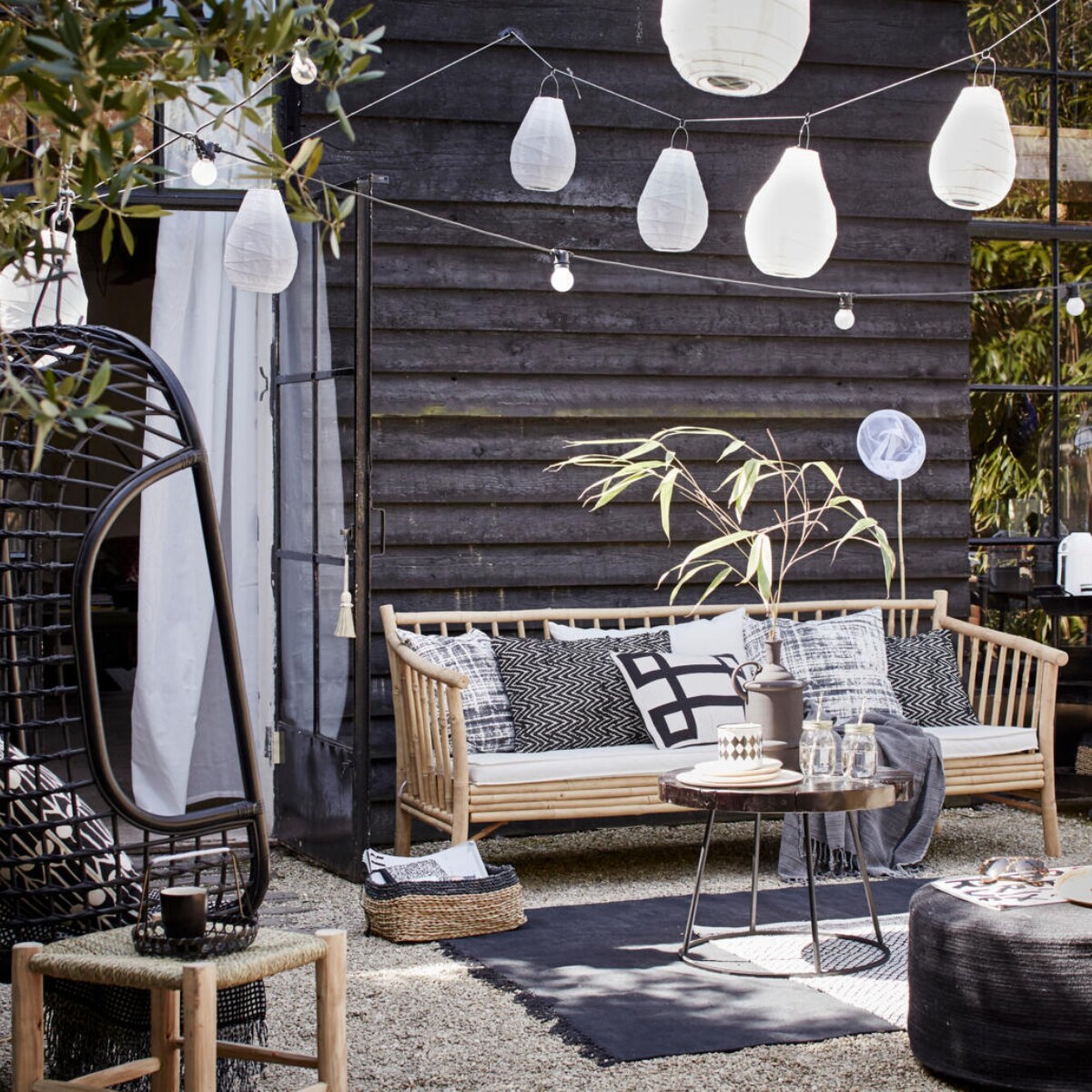 Bamboe bank van Tine K Home, 190 cm breed € 675,- (l’Etoile Conceptstore). Kussens op de bank van linksaf: hoes met vervaagde ruit, Worn van House Doctor, 50x50 cm € 17,95, zigzagkussen Graphy van Casa Vivante 60x40 cm € 29,95, wit kussen met zwart grafisch motief Lifestyle Manhattan 50x30 cm € 34,95 (www.vtwonen.nl). Plaid € 44,- (Hammam 34). Rotan hangstoel van HK Living € 199,95 (www.vtwonen.nl). Erin kussen Feathers van Littlephant, 50x50 cm € 65,95 (Livv Lifestyle). Plaid € 29,99 (H&amp;M). Marokkaanse gevlochten kruk van HK Living, groot 37x37x42 cm, klein 31x31x25 cm, samen € 65,-, salontafel Kraton van Dutch Bone, Ø 60 cm € 169,-; matzwarte vaas van Madam Stoltz € 44,95, juten poef van HK Living, 30x70 cm (hxØ) € 149,- (www.vtwonen.nl). Mason Jar drinkbekers set van 4 € 9,95 (vtwonen.nl). Houten bordjes € 6,95 van HK Living, emaillen zwart-wit potje set van 2 € 9,95 (www.vtwonen.nl). Rieten hoed € 39,95 (Sukha Amsterdam). Vloerkleed Stack van House Doctor € 164,95; zwarte rotan stoel van House Doctor € 245,- (www.vtwonen.nl). Zwart-wit vloerkleed € 29,99 (H&amp;M). Lampions Drop van House Doctor, 30x20 cm (hxØ) per 2 € 9,95 en 35x24 cm (hxØ) per 2 € 12,95, lichtsnoer Bella Vista van Seletti, 10 lampen, 14,2 meter € 99,- (www.vtwonen.nl). Visnet € 3,95 (Sissy-Boy Homeland). Gordijn set van 2 € 9,95 (Ikea). Rieten lage manden van Serax set van 3 € 79, (www.vtwonen.nl). vtwonen 2015-06 | Fotografie Alexander van Berge, styling Cleo Scheulderman