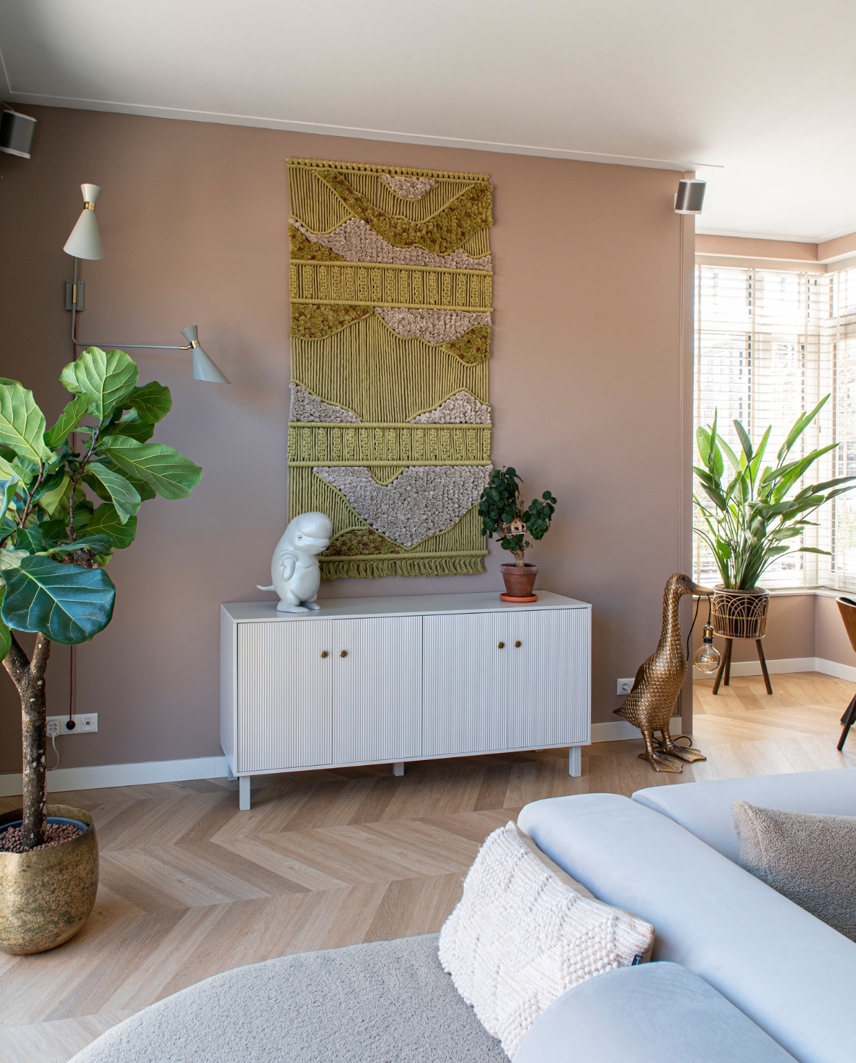 Ficus Green Bubble, pot GroenRijk. Wandlamp Zuiver, wandkleed zelfgemaakt, muurverf Dead Salmon Farrow &amp; Ball. Dressoir Woood, beeld Beluga van Ornamante, Eendlamp Loods 5, plantenstandaard Made, bank 4x6Sofa, pvc-vloer in Hongaarse punt Chevron 6541 van Therdex. Overig onbekend. vtwonen 05-2023 | productie De Binnenkijkers | styling Jeske Weel | fotografie Caroline Coehorst