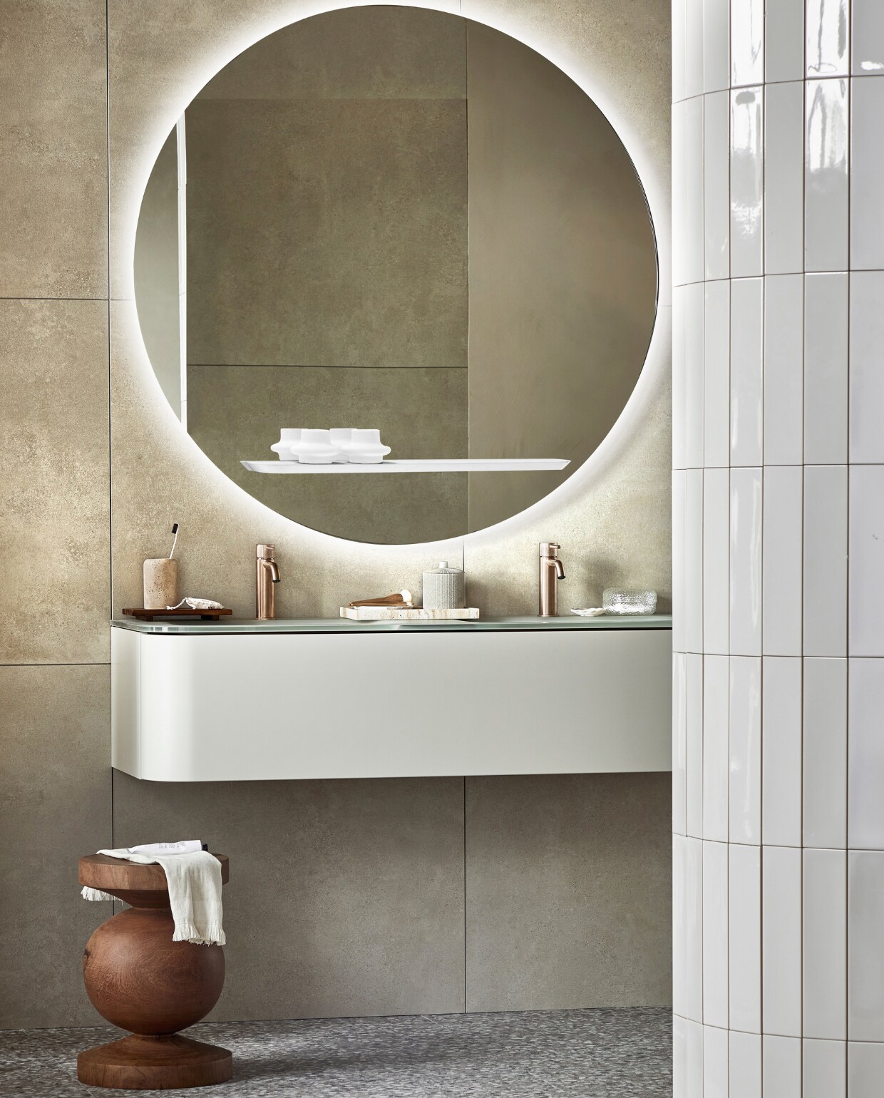 Spiegel Reflect, inclusief ledlicht en condensvrij, 120 cm (Ø) ( ), ook in 80 cm (Ø) ( ). Top solid onderkast Bend in Zand met push to open-systeem, 130x48x31 cm (bxdxh) € ( ), ook in 31x90x48 cm ( ). Vloer: vloer- en wandtegel Terrazzo Clay Flakes, 90x90 cm ( ). Achterwand: vloer- en wandtegel Raw Sand Mat, 80x80 cm ( ). Op de ronde wand: wandtegel Shapes Vapor glans, 7,5x30 cm ( ). M.m.v. plieger.nl (wastafelkranen Roma), polspotten.nl (houten kruk), zarahome.com (travertin tandenborstelhouder, houten dienblad, travertin dienblad, pot met deksel, kwasten, kleine witte schaal, tube crème), hm.com (handdoek, badmat, glazen doosje). Overig privébezit. Beeld vtwonen 05-2023 | productie Tanja Saarberg | styling Sanne Ketelaar | fotografie Peggy Janssen