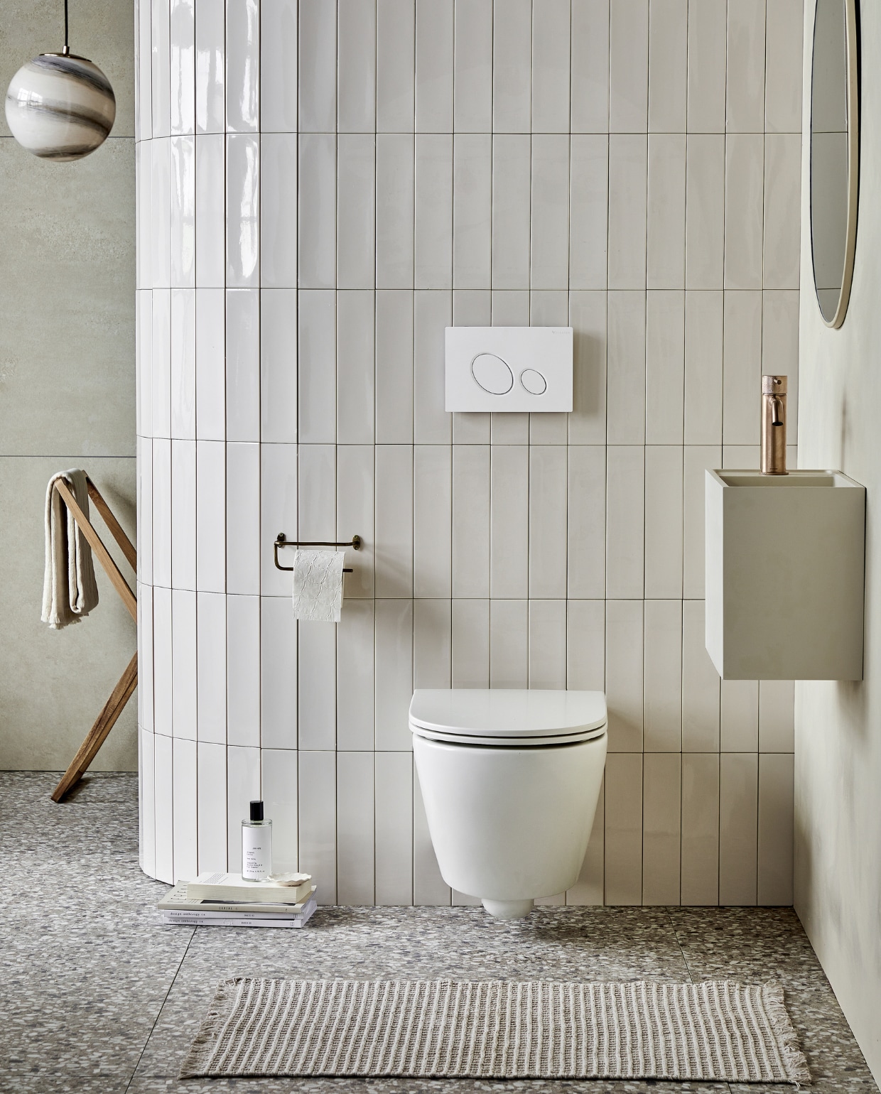 Keramieken toilet Bloc in Mat Wit, met soft close-zitting, ook in matzwart en matzand. Top solid toiletwas-tafel Wide in zand, 40x30x22 cm (bxdxh) ook in grijs, wit en zand en in materialen marmer wit, bruin, zwart en zilvergrijs. Op de vloer: vloer- en wandtegel Terrazzo Clay Flakes, 90x90 cm. Op de afgeronde muur: wandtegel Shapes Vapor glans, 7,5x30 cm. Op de achterwand: vloer- en wandtegel Raw Sand Mat, 80x80 cm. M.m.v plieger.nl (wastafelkraan Roma), vtwonen.be/shop (hanglamp van Bloomingville), zarahome.com (roomspray, houten wasrek, handdoek, messing toiletrolhouder, ronde spiegel), hm.com (badmat). Overig privébezit. vtwonen 05-2023 | productie Tanja Saarberg | styling Sanne Ketelaar | fotografie Peggy Janssen