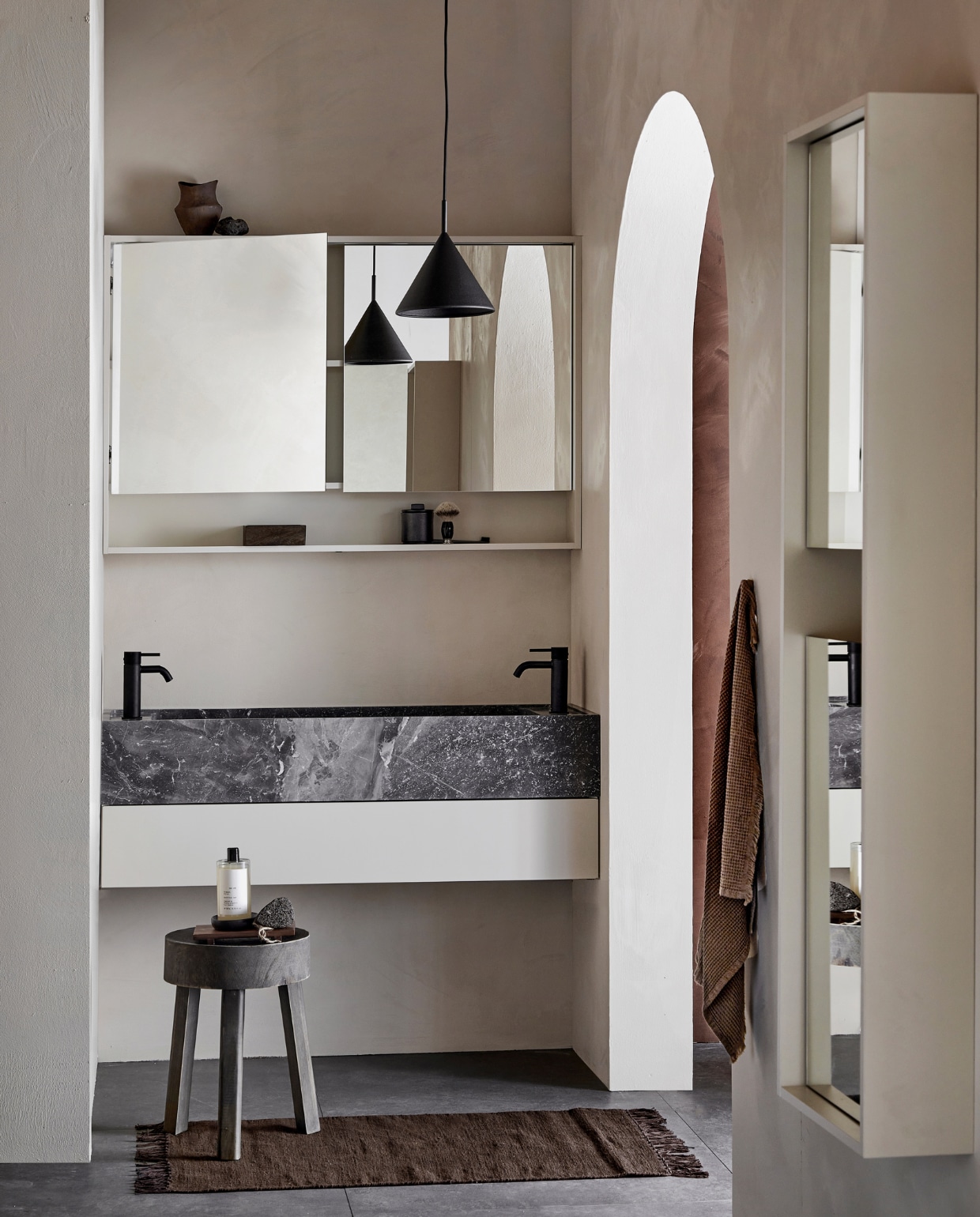 Marmeren wastafel Wide in Silver, 120x41x15 cm (bxdxh), ook in bruin, zwart en wit, met top solid mat gelakte onder-kast Tidy met push to open-lade in Zand, 120x40,5x20 cm (bxdxh), ook in wit, grijs en zwart. Kunststof spiegelkast Handy Beauty met dubbelzijdige spiegeldeuren in Mat Zand, incl. ledstrip met bewegingssensor, 120x16x80 cm (bxdxh), ook in zwart, wit en grijs. Kunststof kolomkast Handy Beauty Long met spiegeldeuren in matzand,  40x16x150 cm (bxdxh), ook in wit, grijs en zwart. Vloer- en wandtegel Raw Antracite Mat, 80x80 cm. M.m.v. plieger.nl (kranen Roma), vestingh.nl (muurverf Ibiza Rush en rechts Holy Monkey van Lab Paint), vtwonen.nl/shop (badmat van Ferm Living, lampen van HKliving), basiclabel.nl (kruk), zarahome.com (pot, schaaltje, dienblad, bodywash), hm.com (bakje, handdoek), bijenkorf.nl (scheerkwast). Overig privébezit. vtwonen 05-2023 | productie Tanja Saarberg | styling Sanne Ketelaar | fotografie Peggy Janssen
