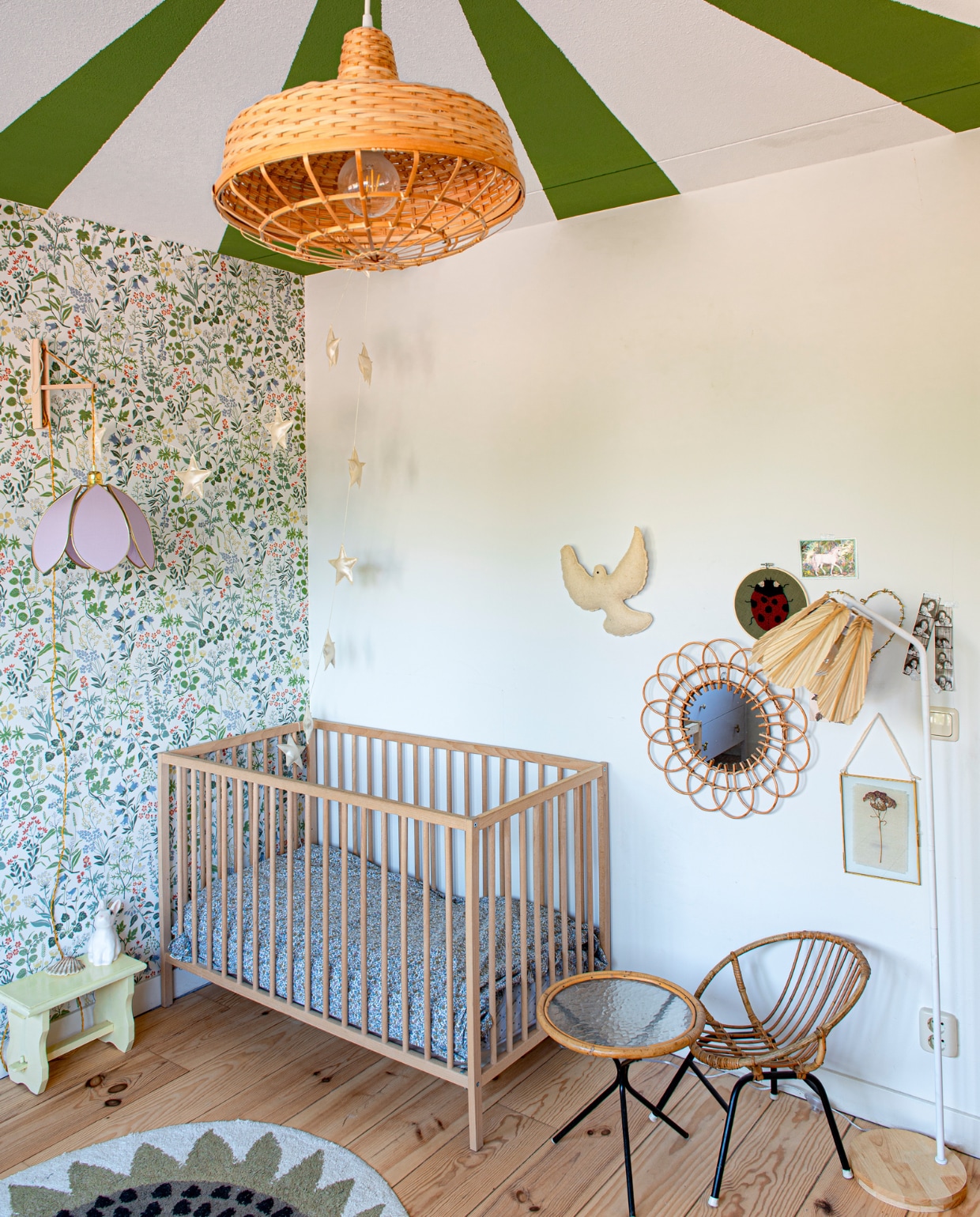 Behang Borastapeter van Store Of Daydreams. Ledikant en kruk tweedehands. Wandlamp Silly &amp; Billy. Hanglamp Ikea. Vogel KidsDepot. Rieten spiegel Xenos. Rieten meubels familiestuk. Dinokleed Tapis Petit. Staande lamp Maisons du Monde. binnenkijk-special vtwonen 131-2023 | fotografie Caroline Coehorst