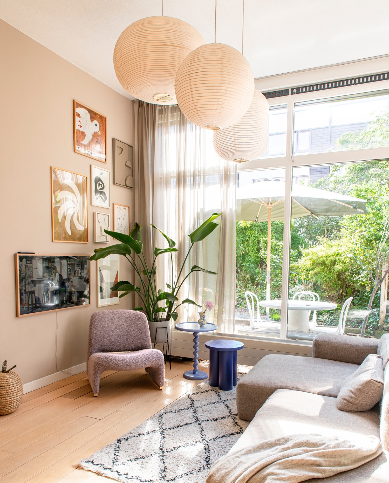 Muurverf Jitney van Farrow & Ball. Bank en hanglampen Hay. Plaid H&M Home. Vloerkleed Karwei. Vintage fauteuil Alky van Artifort via Morentz. Hoge bijzettafel Polspotten, lage Noo.ma. Tv Samsung. Kunst aan de muur o.a. Fly To Tokyo van Mogu Takahashi, Edith Beurskens en Enkel Art. Plantenbak Fonq. Rieten mand Hema. Tafel en stoelen buiten Loods 5. vtwonen binnenkijken special 131-2023 | fotografie Caroline Coehorst