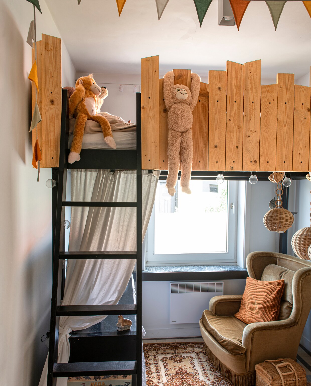 Hoogslaper van Ikea tweedehands gekocht en betimmerd met hout. Vlaggenlijn, lichtsnoer en kussens Hema. Fauteuil, tapijt, lampen en mand kringloopwinkel. vtwonen 06-2023 | productie De Binnenkijkers | styling Jeske Weel | fotografie Caroline Coehorst