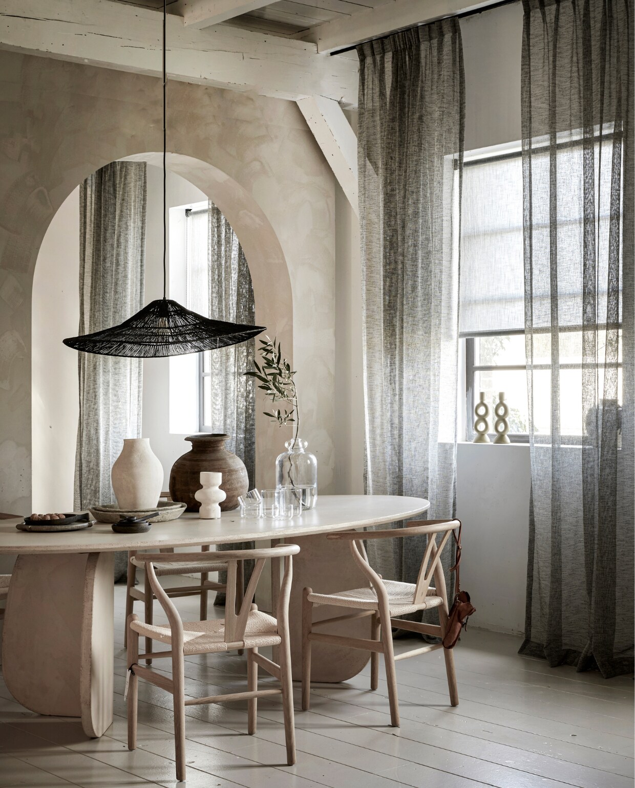 Inbetween gordijn op maat met enkele plooi in stof Weave (2712) kleur Brush vanaf € 32,99 per strekkende meter. Lichtdoorlatend rolgordijn op maat in kleur antraciet structuur (kleurnr: 18015), vanaf € 128,19. M.m.v.: bogard.eu (ovale eettafel), vtwonen.nl (vaas met oren, glazen, mango houten schalen en borden, op de vloer vtwonen lakverf kleur Flax), rawmaterials.eu (diverse vazen op tafel), pure-original.com (kalk muurverf Fresco in kleur Canvas), loods5.nl (eetkamerstoel Tao, hanglamp Coco). In vensterbank: basiclabel.nl (kandelaar Gab van BePureHome). Overig privébezit. vtwonen 06-2023 | productie Tanja Saarberg | styling Marit Saladini Platjouw | fotografie Peggy Janssen