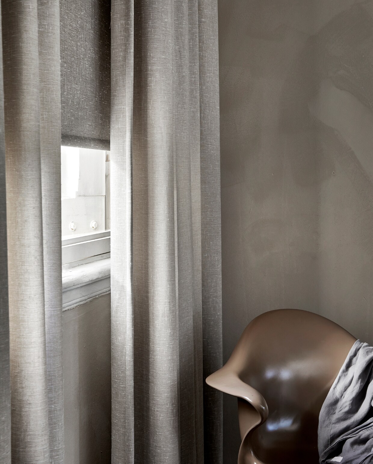 Lichtdoorlatend gordijn op maat, met dubbele plooi in stof Grain (1772) kleur Kiezel vanaf € 26,99 per strekkende meter. Lichtdoorlatend rolgordijn op maat in kleur slub (18007) vanaf € 110,50. M.m.v.: hkliving.nl (eetkamerstoel Sedia moka), pure-original.com (kalk muurverf Fresco in kleur Canvas), hm.com (kamerjas). vtwonen 06-2023 | productie Tanja Saarberg | styling Marit Saladini Platjouw | fotografie Peggy Janssen