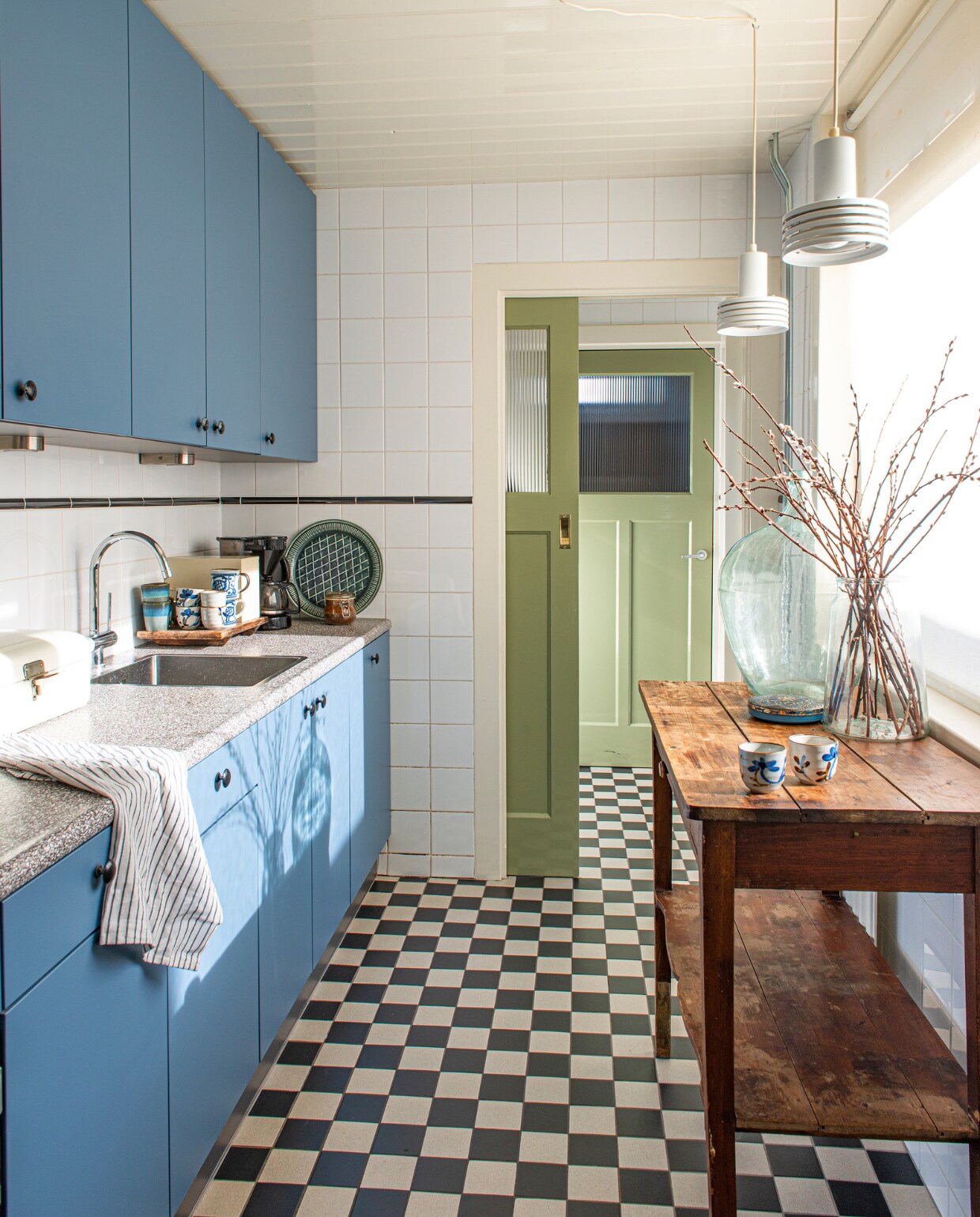 De keuken zat al in het huis. Vloertegels Mosa. Hanglampen, tafel en bolvaas tweedehands. Chinese kopjes en broodtrommel familiestukken. Mokken HKliving. vtwonen special binnenkijken 03-2023 | productie De Binnenkijkers | styling Jeske Weel fotografie Caroline Coehorst