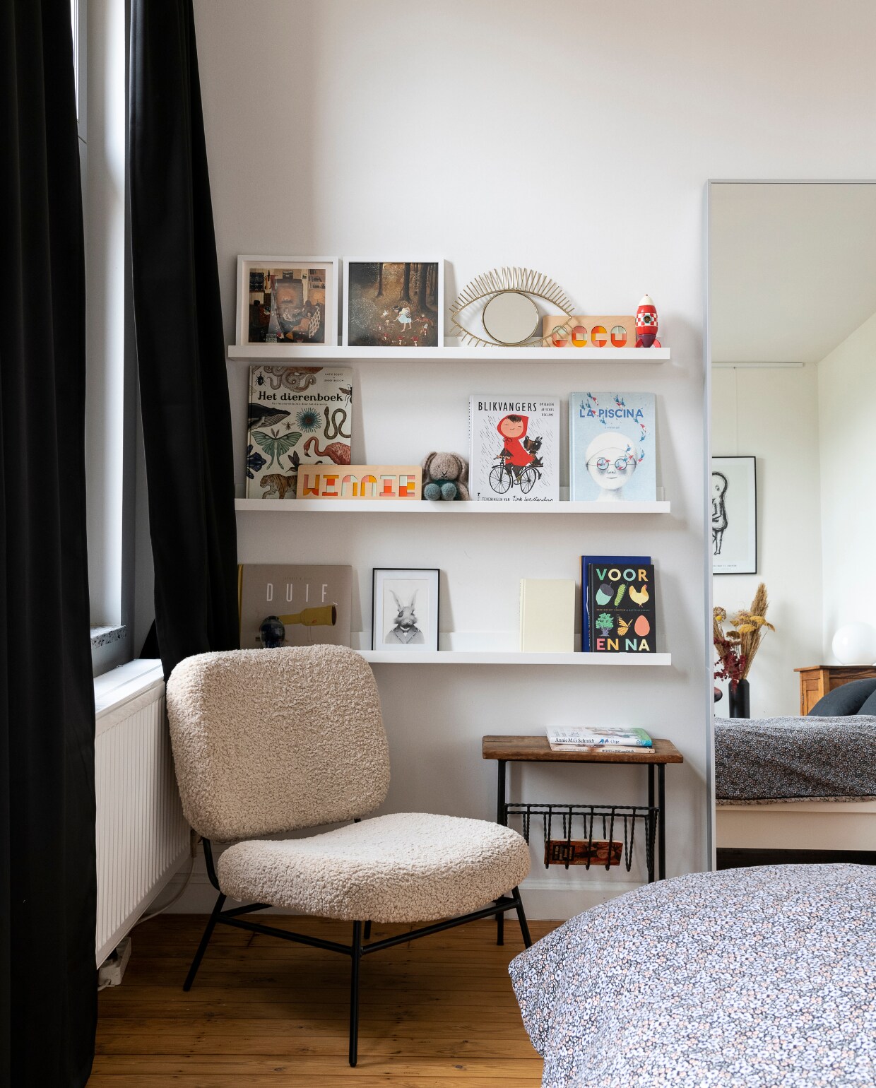 Fauteuil Zara. Gordijnen, spiegel, bed en wandplanken Ikea. Krantenrek sis.antwerp, oogspiegel en beddengoed H&amp;M. Raket Janod, prints A wilder home, naampuzzels Cre8, konijnenknuffel Apella Knits. In het spiegelbeeld te zien: poster The Birth Poster, nachtkastje vintage. Vloer (originele) grenen planken met kleurloze olie. Overig onbekend. vtwonen 06-2023 | styling &amp; fotografie Jonah Samyn