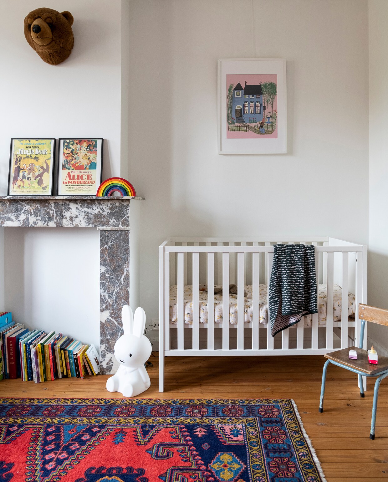 Ledikant tweedehands, beddengoed Garbo &amp; Friends. Stoel vintage, vloerkleed Ikea. Vintage print Alice in Wonderland, speelgoedregenboog kringloopwinkel, poster Fiep Westendorp, lamp Nijntje Mr Maria, berenkop Wild&amp;Soft. Vloer (originele) grenen planken met kleurloze olie. vtwonen 06-2023 | styling &amp; fotografie Jonah Samyn