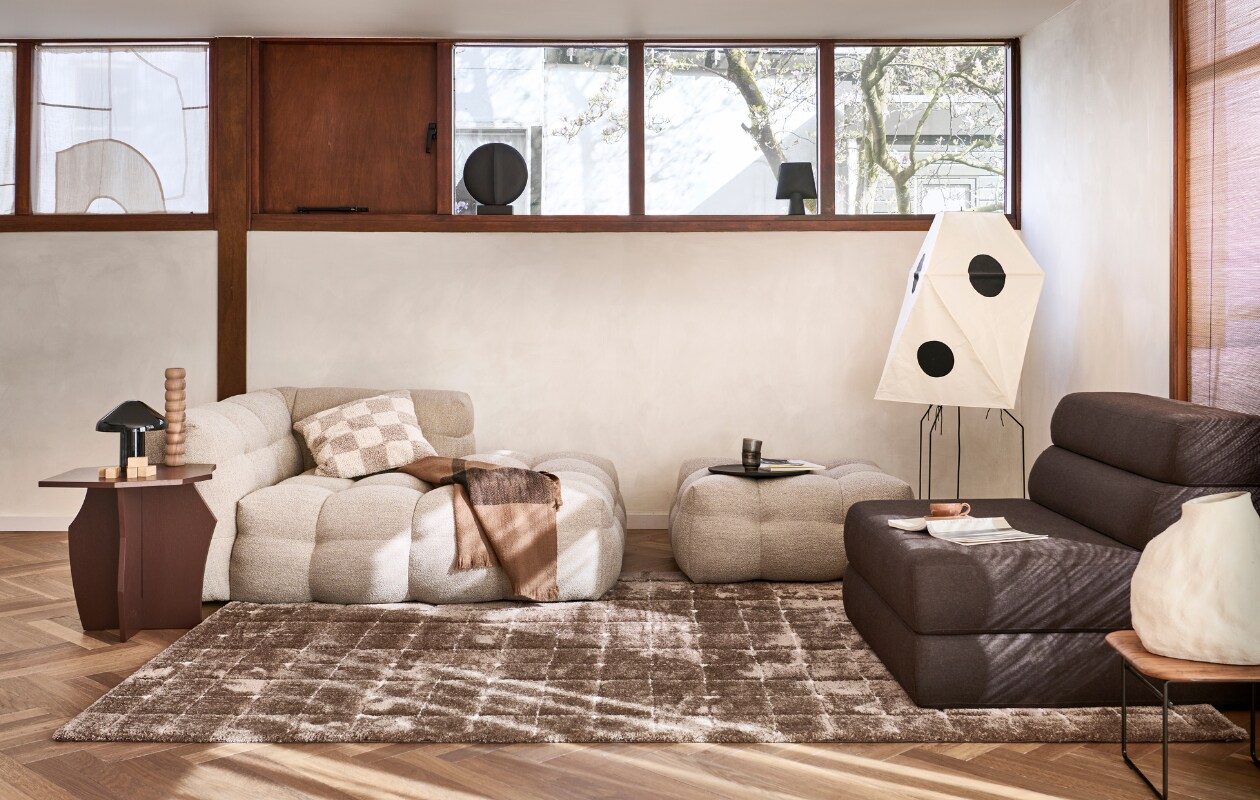 Vloerkleed Blocks in Warm brown, polyester en jute, 200x290 cm. Ook verkrijgbaar in Warm white. M.m.v. loods5.nl (bank Fat Joe, hocker Fat Joe, waterglazen), studiohenk.nl (zitelement Layers, bruine bijzettafel), homestede.nl (houten kandelaar, ronde zwarte vaas, zwarte vaas, stenen dienblad, witte aardewerken vaas), vitra.com (papieren vloerlamp), vtwonen.be/shop (zwarte tafellamp van Hay, plaid van Ferm Living), hm.com (geblokte kussenhoes), lennebelle.com (mok). Overig privébezit. vtwonen 06-2023 | productie Tanja Saarberg | styling Sanne Ketelaar | fotografie Sjoerd Eickmans | assistentie Evans van der Sluis