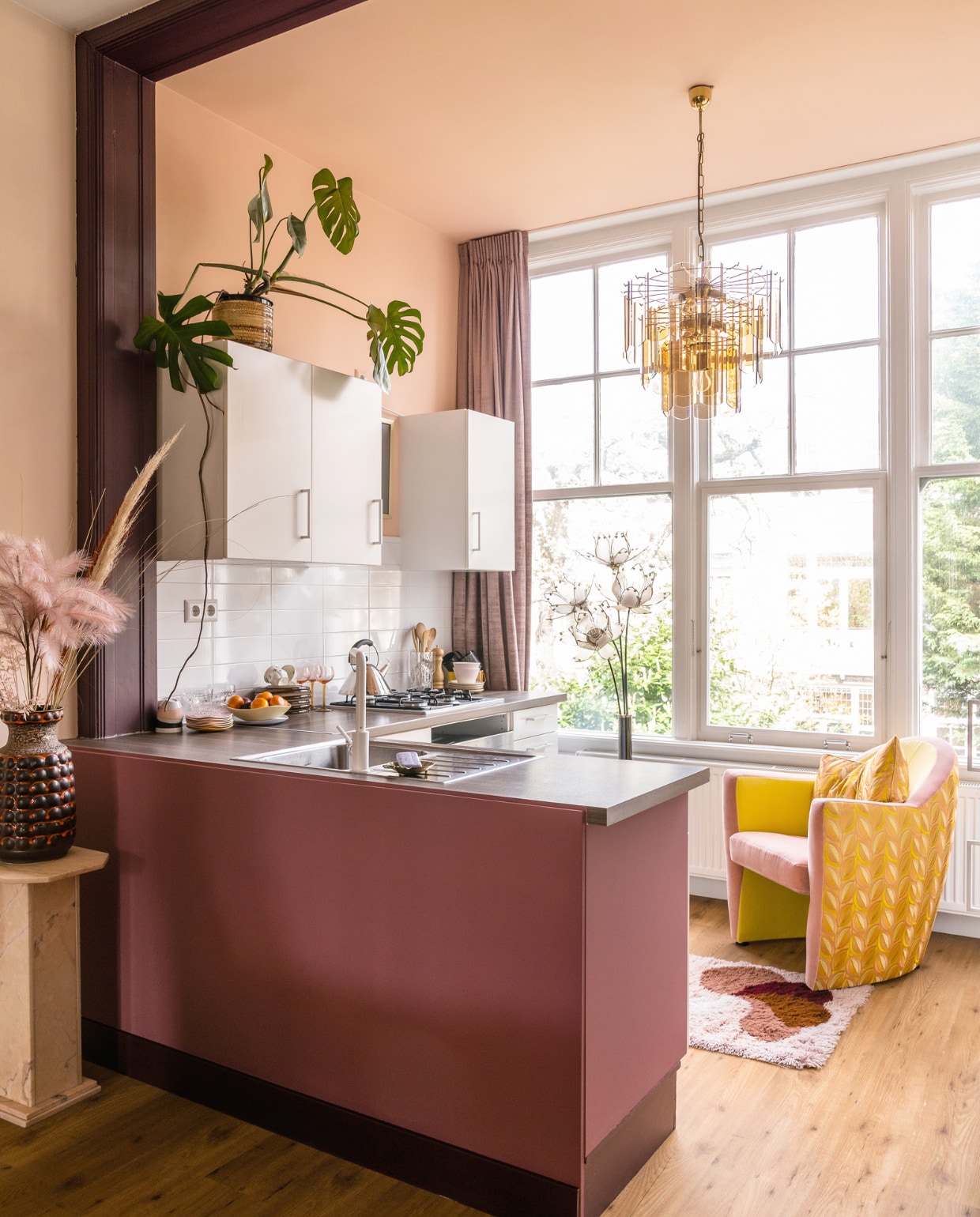Verfkleur muren E0.15.75 van Flexa, keukenombouw A5.16.41 en toog Z9.19.12 van Sikkens. De keuken zat al in het huis. Kroonluchter, vaas en bloempot Sprinkelhop. Marmeren zuil en fauteuil Carabas van Leolux met Casal-bekleding Mippies. Vloerlamp The Mot Regency. Vloerkleed Desso van Decennia Design. vtwonen special binnenkijken 03-2023 | productie CocoFeatures | fotografie Muk van Lil