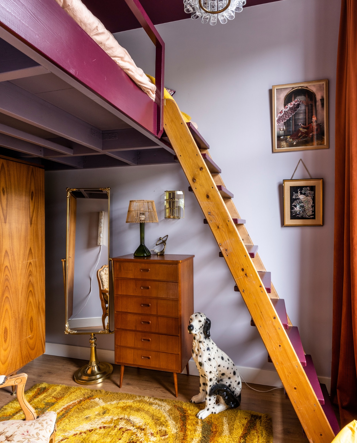 Verfkleur muren Calluna van Farrow &amp; Ball, plafond en bed Z9.19.12 van Sikkens. Bed op maat gemaakt door SFT Dienstverlening met oude zoldertrap. Hanglamp Doria, ladekast, tafellamp van Kastrup Holmegaard, passpiegel, beeldje, vitrinewandkast en hond Sprinkelhop. Vloerkleed meutt.nl. Kunst Studio Dnnk en All The Luck in the World. Fauteuil erfstuk. vtwonen special binnenkijken 03-2023 | productie CocoFeatures | fotografie Muk van Lil