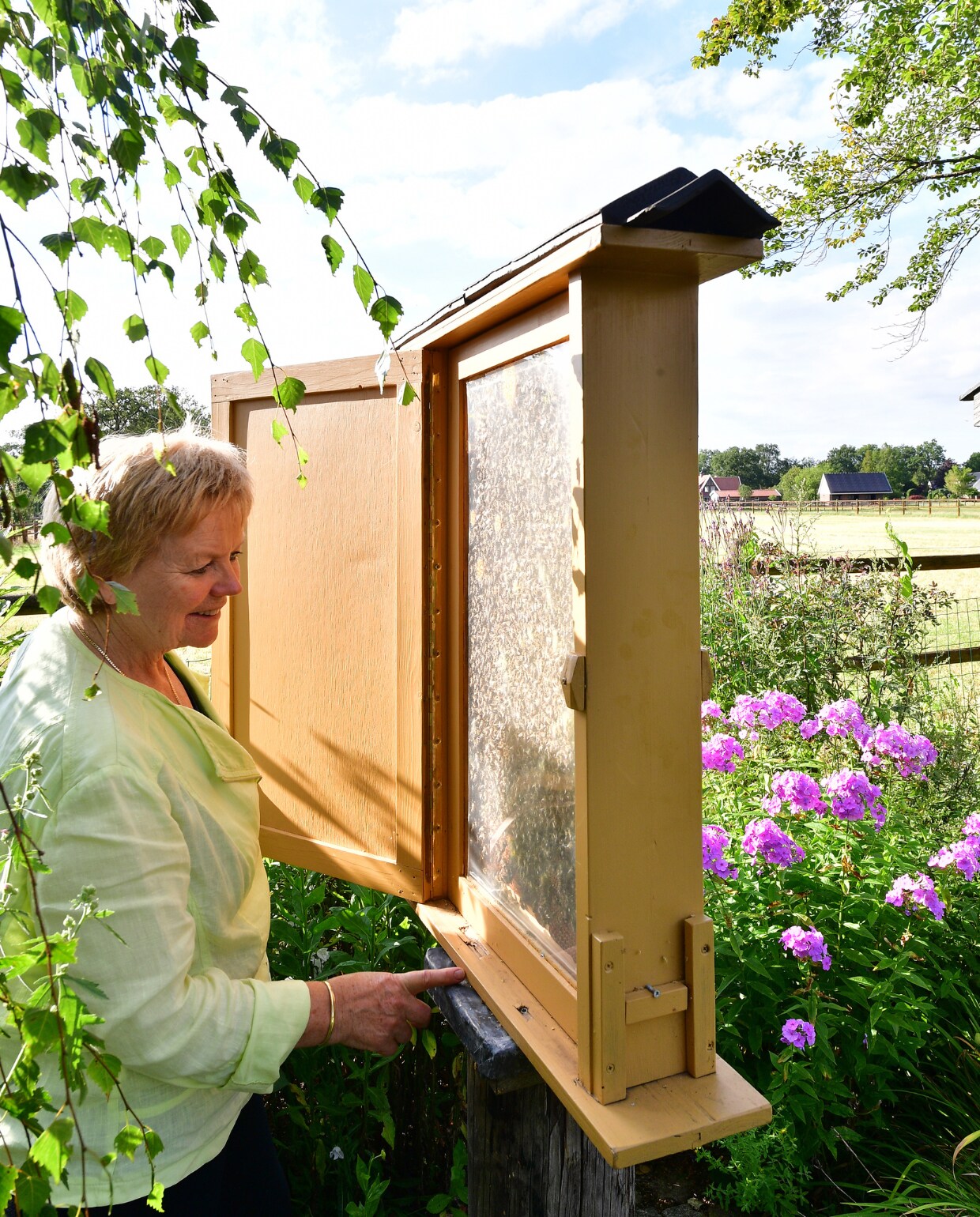 Ina bij haar demonstratiebijenkast. Achter de bijenkast roze phlox. vtwonen special tuin 04 | fotografie Sietske de Vries | styling Ina ter Haar