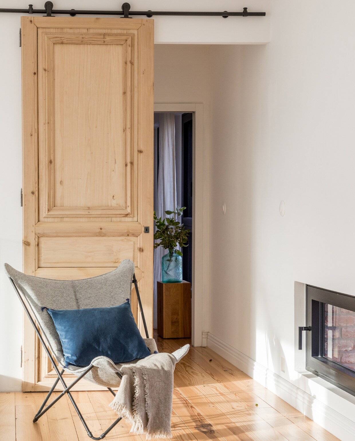 Schuifdeur rommelmarkt, rails bouwmarkt. Vlinderstoel Lafuma, kussen Elitis, plaid Maison de Vacances, haard onbekend. vtwonen 06-2023 | productie AC Scoffoni | styling Marie-Maud Levron | fotografie Cecile Perrinet-Lhermitte