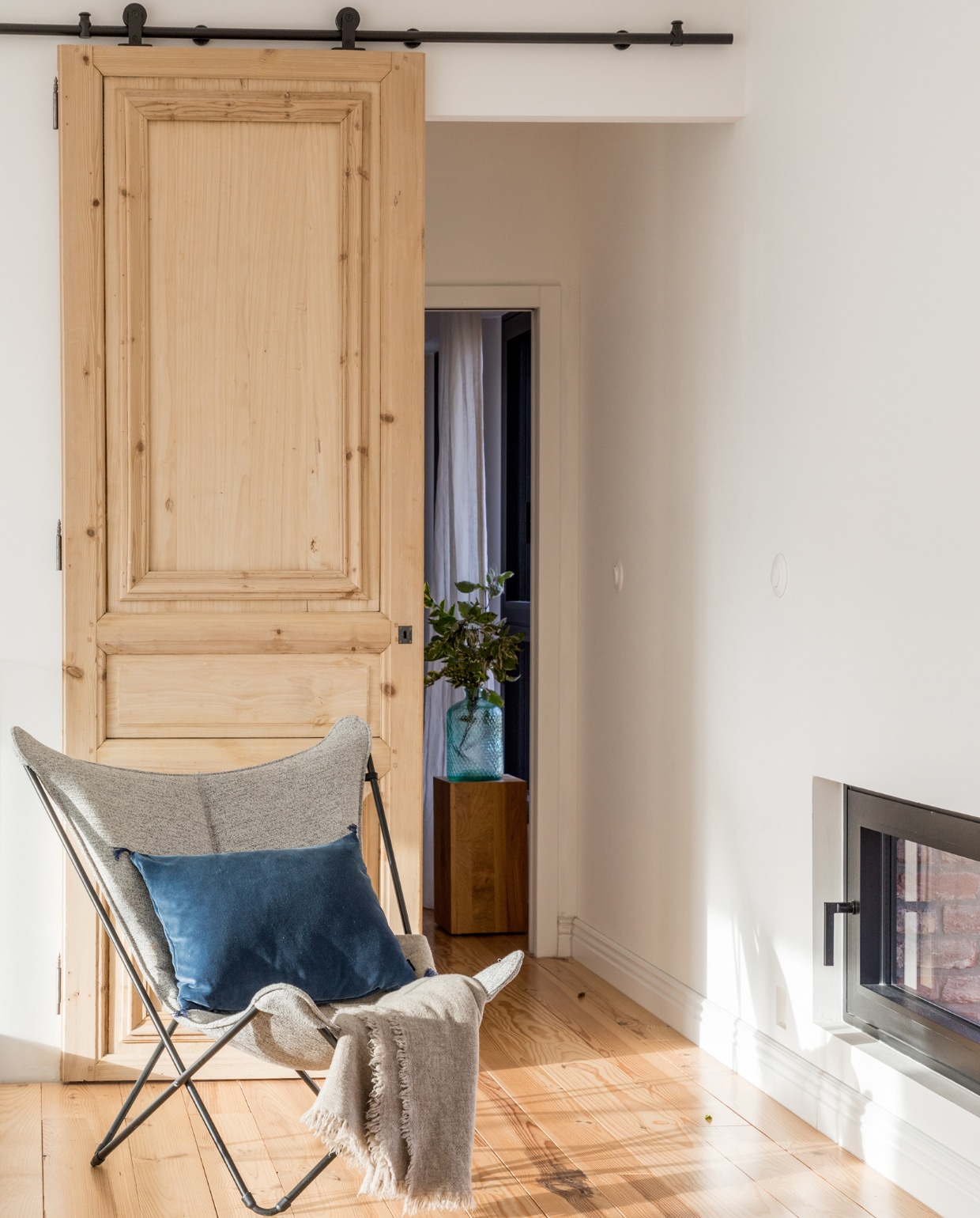 Schuifdeur rommelmarkt, rails bouwmarkt. Vlinderstoel Lafuma, kussen Elitis, plaid Maison de Vacances, haard onbekend. vtwonen 06-2023 | productie AC Scoffoni | styling Marie-Maud Levron | fotografie Cecile Perrinet-Lhermitte