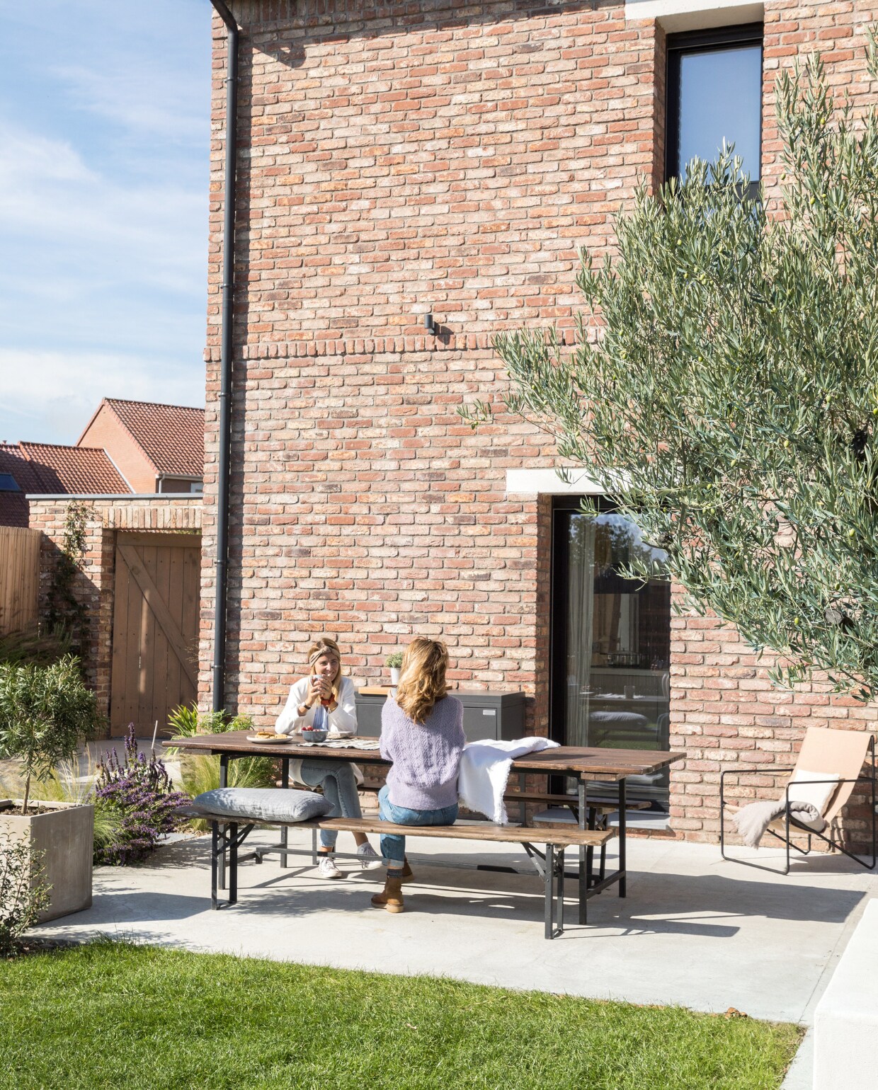 Tafel en banken gered uit een werkplaats, kussens Maison de Vacances. vtwonen 06-2023 | productie AC Scoffoni | styling Marie-Maud Levron | fotografie Cecile Perrinet-Lhermitte