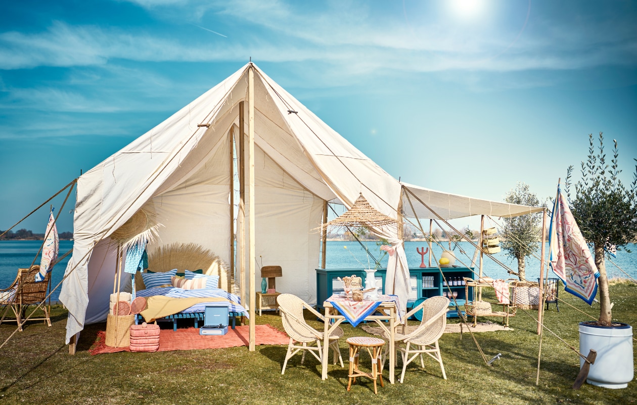 Tent met houten frame, blauwe keuken en daybed van Combitex, prijs op aanvraag (com-anders.nl). Ligstoel Zeya links, rotan kapstok met mand Sio, rotan lamp Atum op nachtkast, yogamat Yin opgerold in kapstok, kleed keuken, 200x75 cm, grote en kleine afdekmanden en grote witte pot, prijs op aanvraag (nordal.dk). Rood-oranje vintage hennep tapijt, 248x 268 cm, kruk Malawi naast bed, bamboe en rotan, hoofdeinde van palmbladeren, dadelpalmtak hanglamp, blauw-wit gestreept linnen dekbedovertrek large, geel dekbedovertrek Straw, bamboe trolley, hoed van palmblad uit Marokko, blauwe fruitschaal tegen keuken (couleurlocale.eu). Tafelkleed en vlag, 90x90 cm, prijs op aanvraag (hm.com). Mand met olijfboom, 53x62 cm (Øxh), fairtrade blauwe jas (weldaad.com). Handgemaakte rotan kruk (ha50.nl). Kleine houten lepel op tafel, kleine houten bak op tafel, kleine houten borden, grote lepel achter op tafel, mand aan tent met 3 etages, houten tafel, houten stoelen, per stuk, snijplank, roze-wit gestreept kussen (householdhardware.nl). Roze mand (dekringloper.nl). Bord citroen in keuken, roze wijnglas, per stuk (maisonnl.com). Platenspeler, beige vaas in keuken, roze kandelaar, oranje-wit geruit servet, set van 2 (sissy-boy.com). Witte vaas Billy van Serax, 31 cm (h), blauwe karaf Fish &amp; Fish van Serax, 1 liter, vuurkorf Modern Ronda van Barbecook, taartplateau Inku van Serax, 24 cm (Ø), fruitmand (vtwonen.be/shop). Blauw-wit gestreepte box in keuken van Hay, radio van Lexon, roze tennisset van Liewood (bijenkorf.nl). Geruit kussen op ligbed, 60x40 cm (letoile.store). Takken, prijs op aanvraag (waterdrinker.nl). Overig privébezit. vtwonen 07-2023 | Styling Liza Wassenaar | Fotografie Sjoerd Eickmans