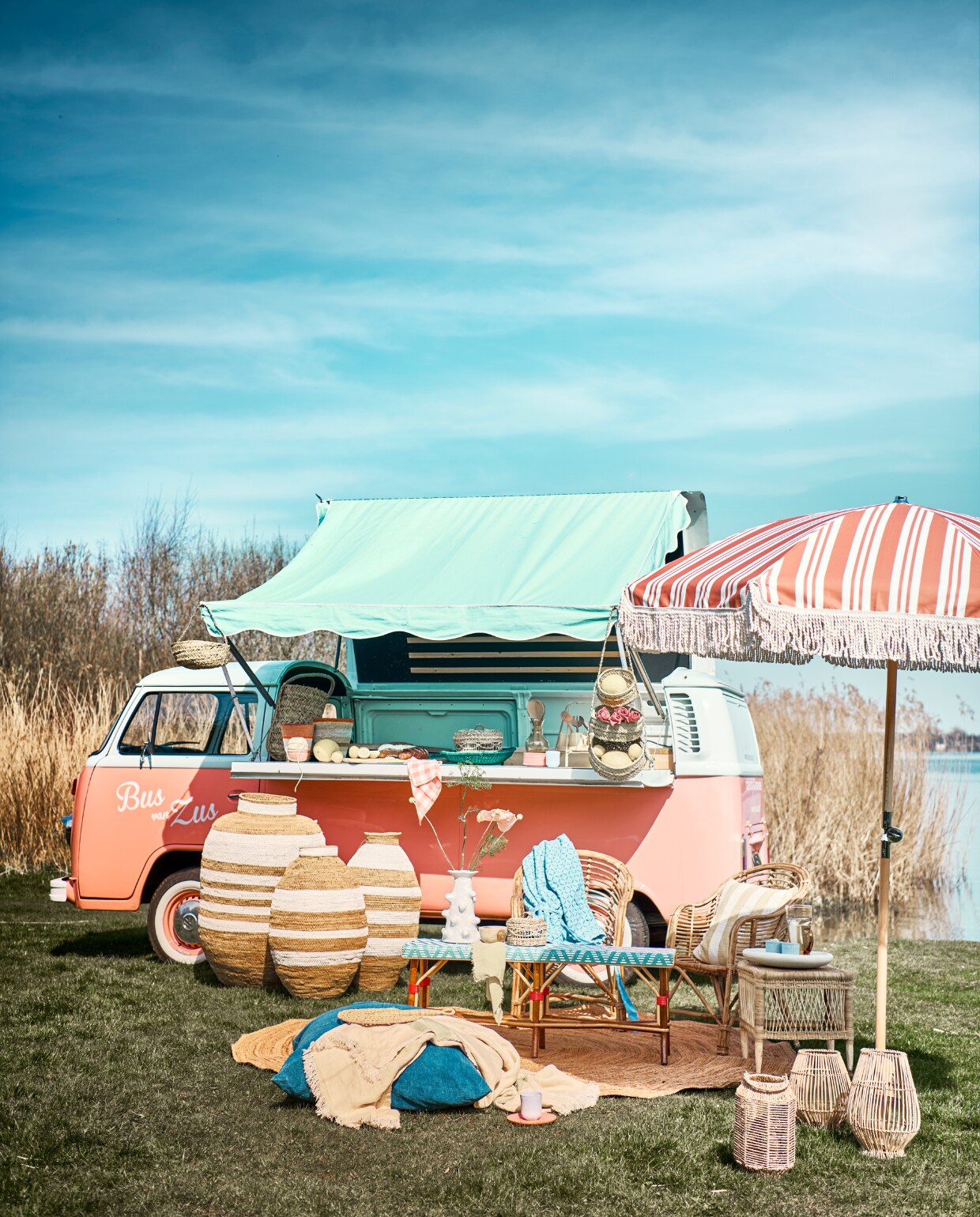 Duurzaam gemaakte rotan bank (ha50.nl). Juten vloerkleed Eternal Natural van Ferm Living, 240 cm (Ø), vaas Billy van Serax, 31 cm (h) (vtwonen.be/shop). Bus gehuurd bij Bus van Zus, prijs op aanvraag (busvanzus.nl). Parasol, 200 cm (Ø), oranje glazen karaf, roze ontbijtborden, 17 cm (Ø), set van 12, gele theeglazen, set van 4, roze-rood gestreepte manden, klein, groot, oranje-wit geruit servet, set van 2 (sissy-boy.nl). Groot blauw kussen Indigo, waaier maat M, wit-beige gestreepte kruiken, blauwe fruitmand, bamboe en rotan Malawi kruk, geel servet Ocher, gele karaf Amber, gele plaid Towel (couleurlocale.eu). Roomwitte schaal op tafel, houten snijplank, slabestek, grote houten lepel, grote mand op bar, kleine mand aan luifel, mand met 3 etages (householdhardware.nl). Zeegras windlicht, blauwe keramieken mokken, roze linnen servet, 45x45 cm, set van 2 (hm.com). Rieten windlichten Silba van Nordal, groot, klein, rotan stoelen Cania, grote en kleine afdekmanden en etagère, prijs op aanvraag (nordal.dk). Fairtrade blauw jasje (weldaad.com). Geel-wit gestreept kussen (bungalow.dk). Takken, prijs op aanvraag (waterdrinker.nl). Overig privébezit. vtwonen 07-2023 | styling Liza Wassenaar | fotografie Sjoerd Eickmans