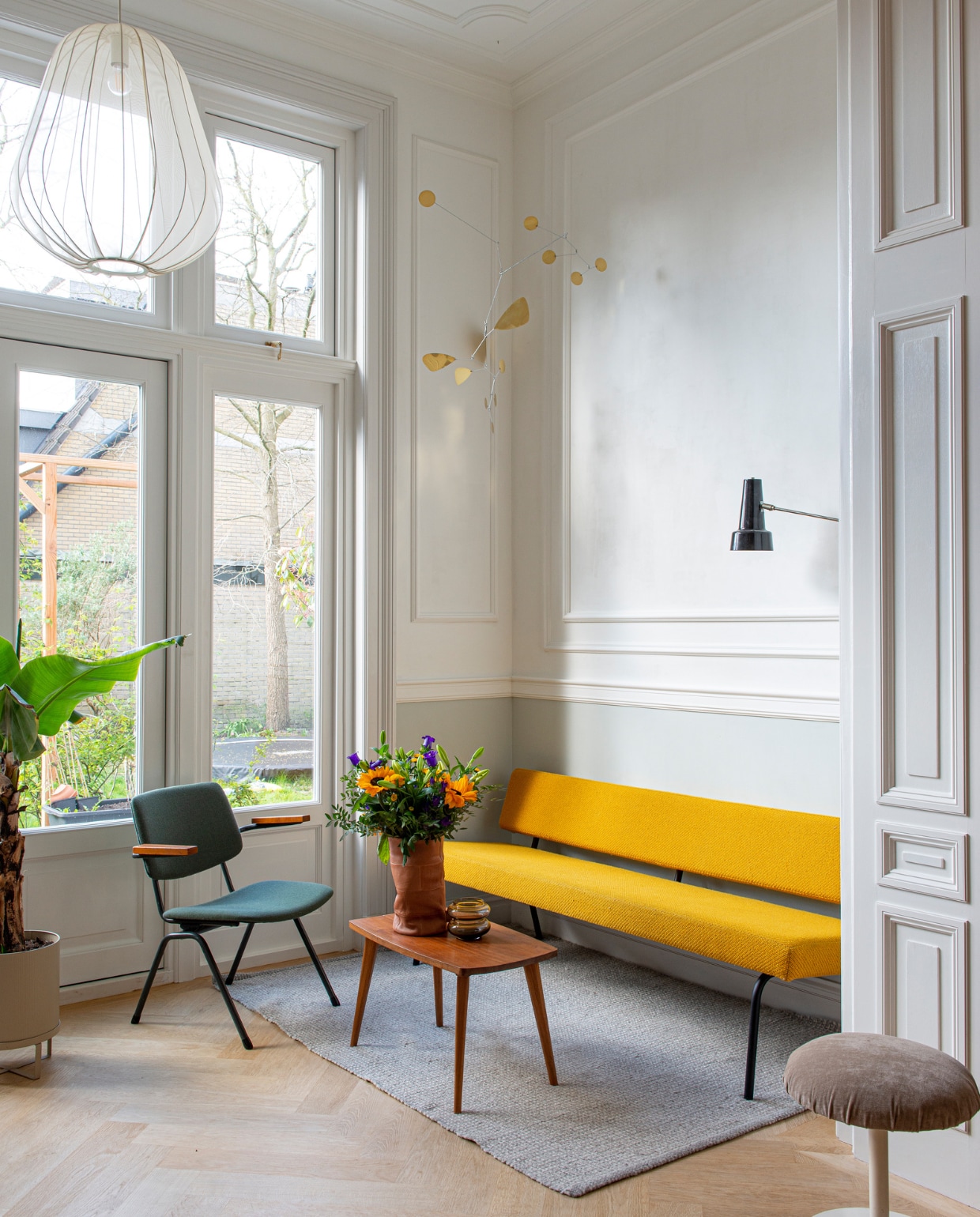 Verfkleur deurlijst Slaked Lime Mid en muur Pearl Color van Little Greene. Vloer Balkan Wood. Bank Fést. Tafel vintage. Fauteuil De Machinekamer. Bloempot Ferm Living. Hanglamp Bolia. Mobile Lappalainen. Hagoort-wandlamp Tijdperk. Hoes om vaas O My Bag. Vloerkleed H&amp;M Home. Kruk Meutt. vtwonen special binnenkijken 03-2023 | productie De Binnenkijkers | styling Jeske Weel  fotografie Caroline Coehorst