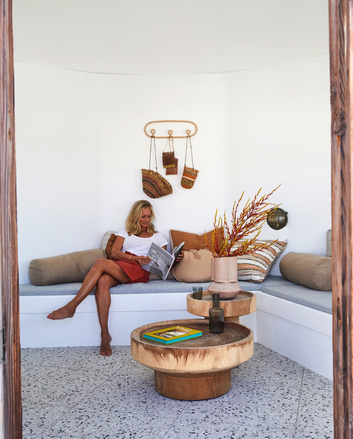 Nina in de torenkamer op het dak. Terrazzo vloertegels Ciottolo Grande van Ceramica Senio. Bijzettafels uit de Rwanda-collectie van Uniqwa Collection. Roze vaas Oval Scallop Vase Tangerine Ice Jardan. Kussens Hale Mercantile. Kapstok Trio Virginia Sin. vtwonen special binnenkijken 06-2022 | productie Living Inside | styling Julia Green | fotografie Armelle Habib