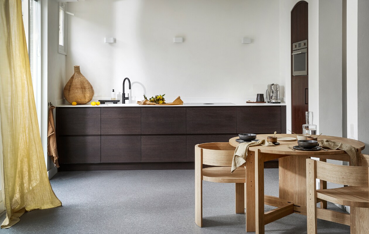 Novilon vloer in Graniet, per m² € 36,75 (excl. installatie). M.m.v. letoile.store (eikenhouten eettafel en stoelen van Kristina Dam, linnen servetten, mokken met schotels van Serax, keramieken servies), justanothershop.nl (knoflookvormige mand, snijplank, zwarte kan), lidor.nl (gordijn van Numero 74). Overig privébezit. vtwonen 07-2023 | productie Tanja Saarberg | styling Marlies Does | fotografie Peggy Janssen | assistentie Lisa Weel
