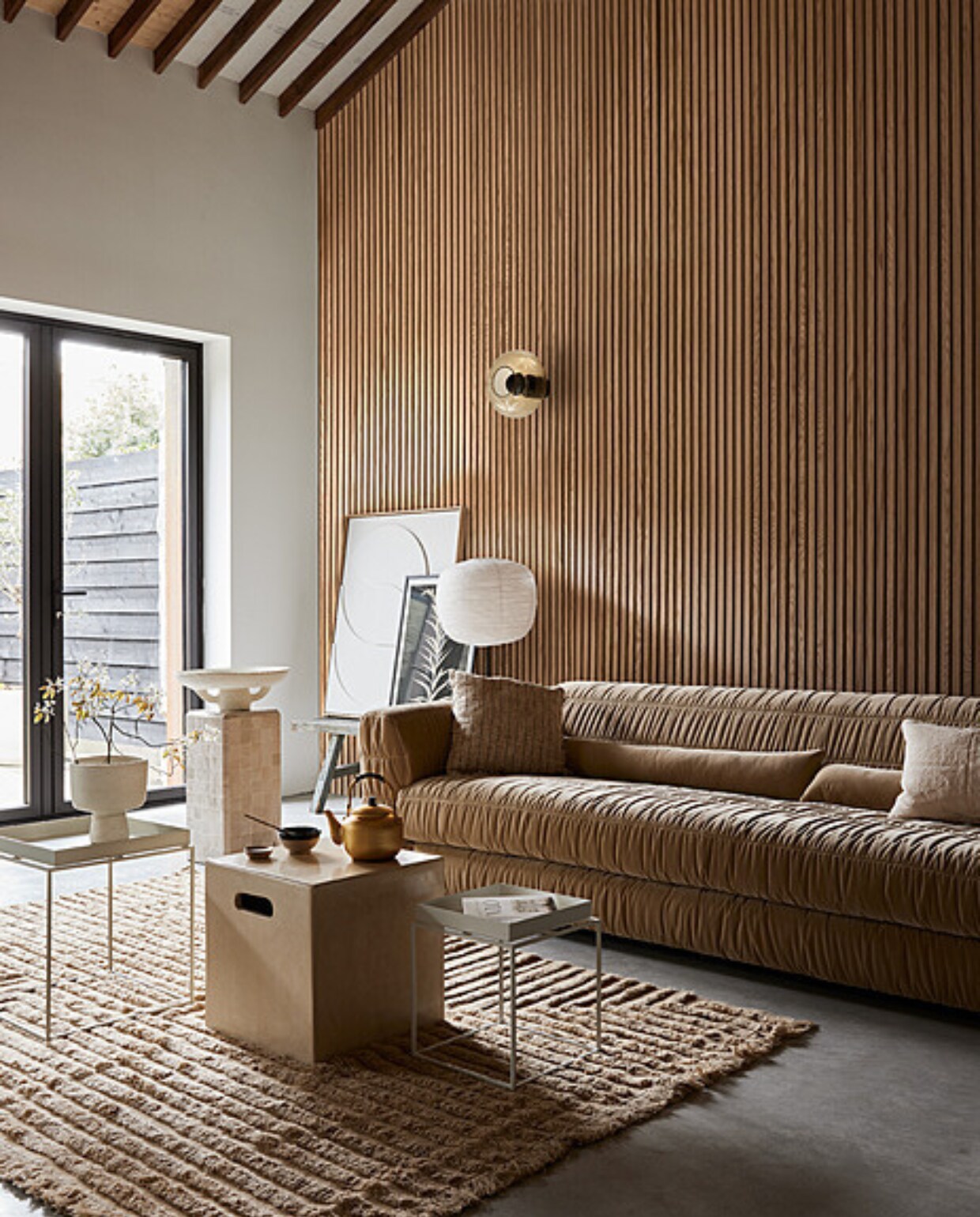 Akoestische wandpanelen van eikenhout en beige vilt, 60x240 cm (bxh) (noakk.nl). Bank Club Couch in Royal Velvet Cream, 108x74x72 cm (bxdxh) (hkliving.nl). Wollen vloerkleed Crease van Ferm Living, 250x160 cm (bxh), katoenen kussen links Febbie van Bloomingville, 45x45 cm, papieren schaal Earth van Serax (vtwonen.nl/shop). Linnen kussen rechts, 50x30 cm (sukha.nl). Rijstpapieren lampenkap Common, 44x39 cm (Øxh), lichtgrijze stalen salontafel Tray, 30x30x34 cm (lxbxh), witte stalen salontafel Tray, 60x40x39 cm (lxbxh) (hay.nl). Tadelakt tafel Cube, 40x40x40 cm (bxdxh), tafel met zelliges, 30x30x60 cm (bxdxh), tadelakt vaas, theepot, kom, walnoothouten schaal (householdhardware.nl). Poster Solidago Gigantea ll van Printedplant, 50x70 cm (pstrstudio.com). Reliëf kunstwerk, 83x103 cm (bxh) (hkliving.nl). Overig privébezit vtwonen 08-2023 | styling Fietje Bruijn | fotografie Alexander van Berge