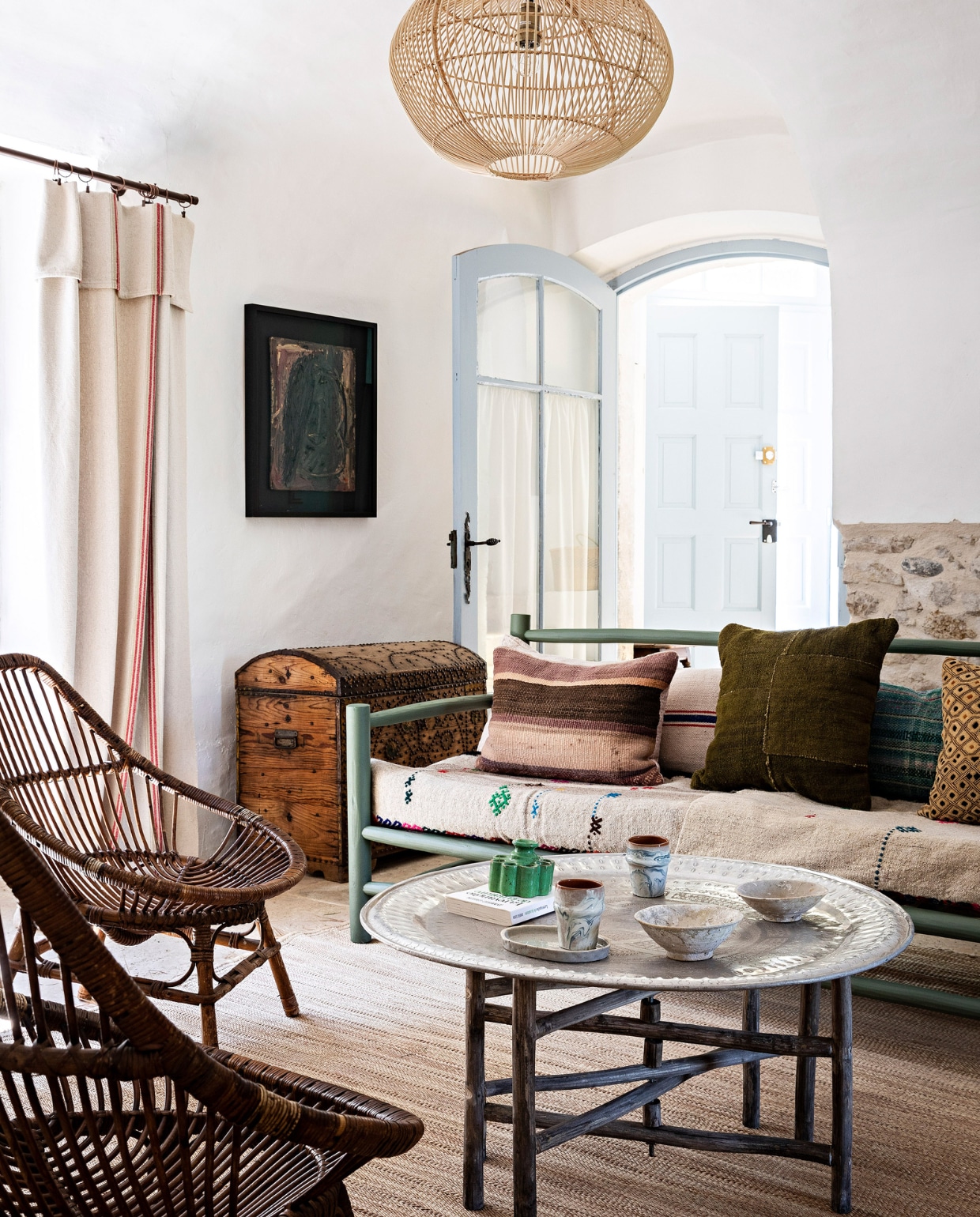 Hanglamp, bank, servies en salontafel van markt in Marrakech, rotan fauteuils en houten kist rommelmarkt. Kussens Maison &amp; Objets-beurs. Vergelijkbare blauwe verf kozijnen en deur: Borrowed Light van Farrow &amp; Ball. Overig onbekend. vtwonen 07-2023 | fotografie Yann Deret