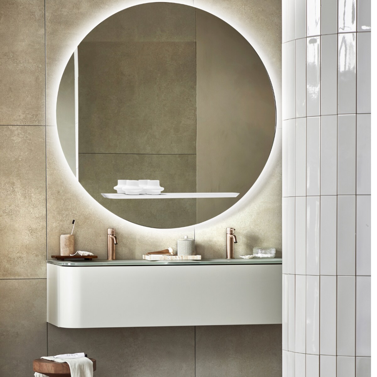 Spiegel Reflect, inclusief ledlicht en condensvrij, 120 cm (Ø), ook in 80 cm (Ø). Top solid onderkast Bend in Zand met push to open-systeem, 130x48x31 cm (bxdxh), ook in 31x90x48 cm . Vloer: vloer- en wandtegel Terrazzo Clay Flakes, 90x90 cm. Achterwand: vloer- en wandtegel Raw Sand Mat, 80x80 cm. Op de ronde wand: wandtegel Shapes Vapor glans, 7,5x30 cm. M.m.v. plieger.nl (wastafelkranen Roma), polspotten.nl (houten kruk), zarahome.com (travertin tandenborstelhouder, houten dienblad, travertin dienblad, pot met deksel, kwasten, kleine witte schaal, tube crème), hm.com (handdoek, badmat, glazen doosje). Overig privébezit. vtwonen 05-2023 | productie Tanja Saarberg | styling Sanne Ketelaar | fotografie Peggy Janssen