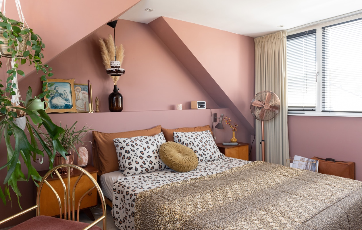 Verfkleur Terra Pink van Vestingh. Gordijnen Karwei. Bed Senza van Karup. Dekbedovertrek Wehkamp. Kussens H&amp;M Home. Messing stoel, nachtkastjes, glazen flesvaas en slaapzak als sprei tweedehands. Zoutlamp natuurwinkel. Schilderijen Bikkel Store. Bedlamp en hanglamp Vintage Friends. Overig onbekend. vtwonen special binnenkijken 03-2023 | styling Sharon Roest | fotografie Caroline Martinot