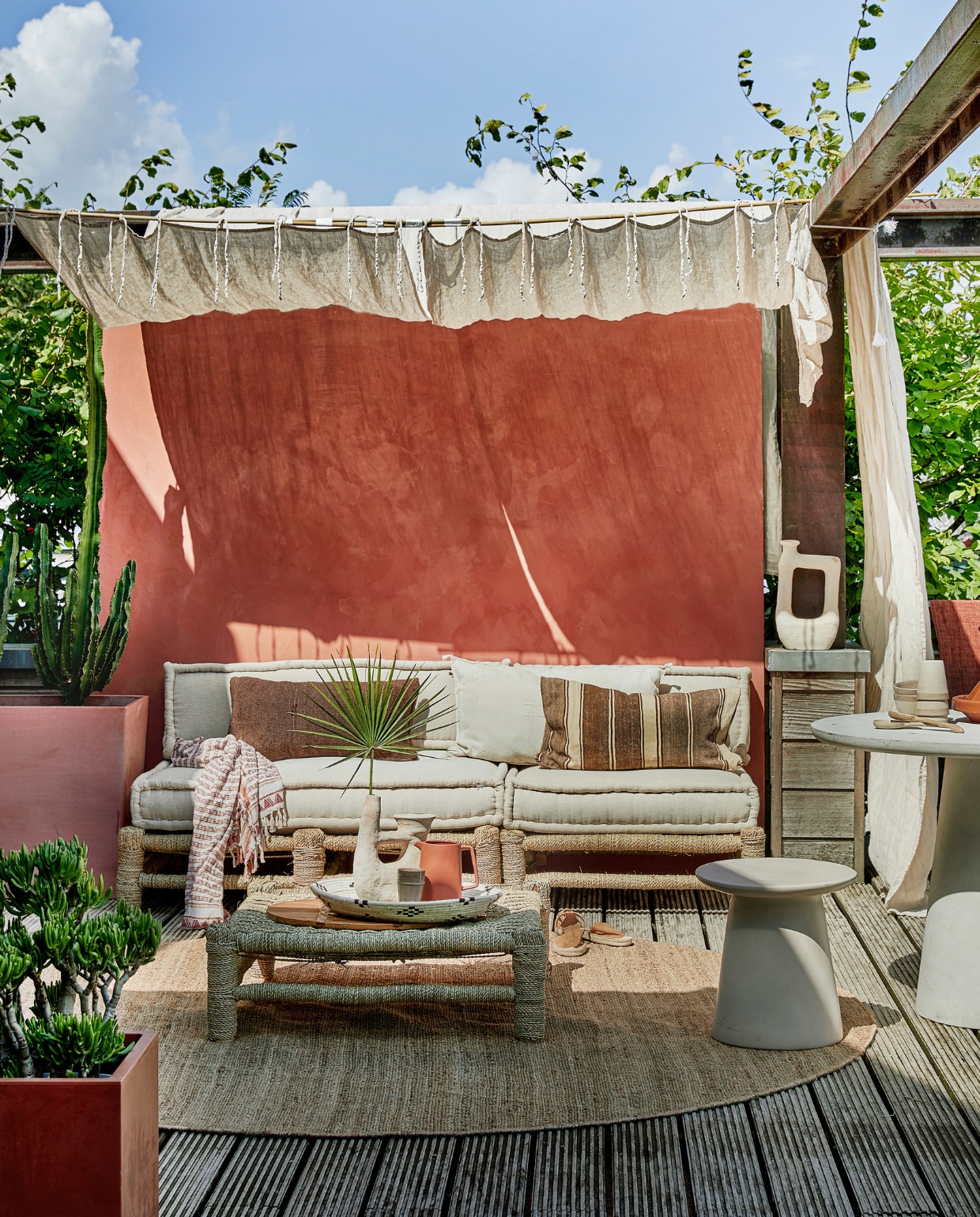 Met touw omwikkelde houten loungebank Hassan, 80x80 cm € 255,-, 120x80 cm € 335,-, zitkussens vanaf € 109,-, zandkleurige vaas Tamegroute met 2 armen € 109,-, zandkleurige vaas Tamegroute jerrycanvorm € 115,-, gevlochten schaal € 11,95, mokken en schaaltjes per stuk € 11,- (householdhardware.nl). Bruine sierkussens per stuk € 63,95, naturel geborduurd kussen Sabra Oblong XL € 99,- (zenzahome.com). Hennep vloerkleed, 250 cm (Ø) € 529,-, zandkleurige keramieken kruk Earthenware € 199,- (hkliving.nl). Espadrilles € 19,99 (hm.com). Fiberclay betonlook tafel Damon € 439,- (woood.nl). Terra karaf Flora € 21,95 (loods5.nl). Naturel linnen gordijnen Classic Sand, per stuk € 94,95 (casacomodo.nl). Hoge terra plantenbak Paris van Ecopots € 329,- (vtwonen.be). Lage terra plantenbak € 45,- (intratuin.). Kalkverf op de muur kleur Marakech CC044, per liter € 52,80 (cartecolori.nl). Overig privébezit. vtwonen special tuin 06 | styling Moniek Visser | fotografie Peggy Janssen | assistentie Mirjam Gesink, Sanne Kiesling